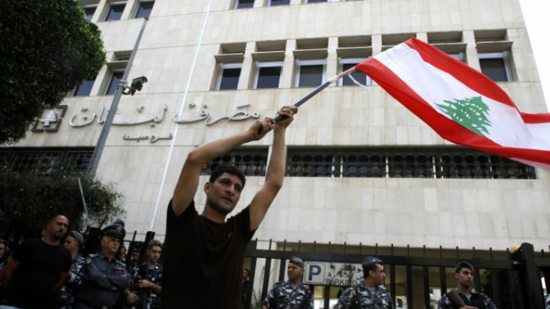 متظاهر يحمل العلم اللبناني خلال تظاهرة أمام المصرف المركزي فرع صيدا في جنوب لبنان في 28 تشرين الأول