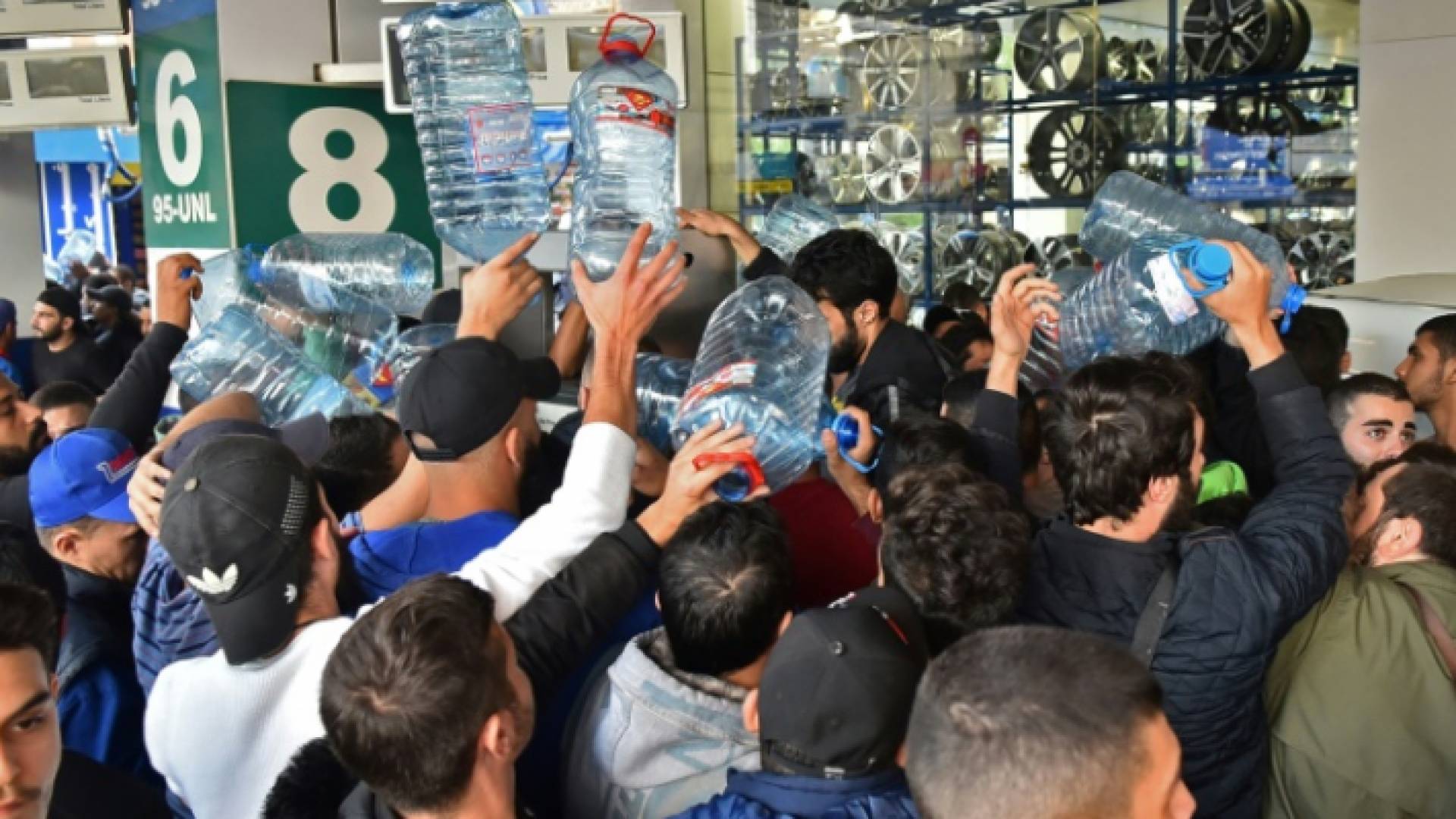 لبنانيون يحملون عبوات بلاستيكية بانتظار تعبئتها من محطة وقود في بيروت