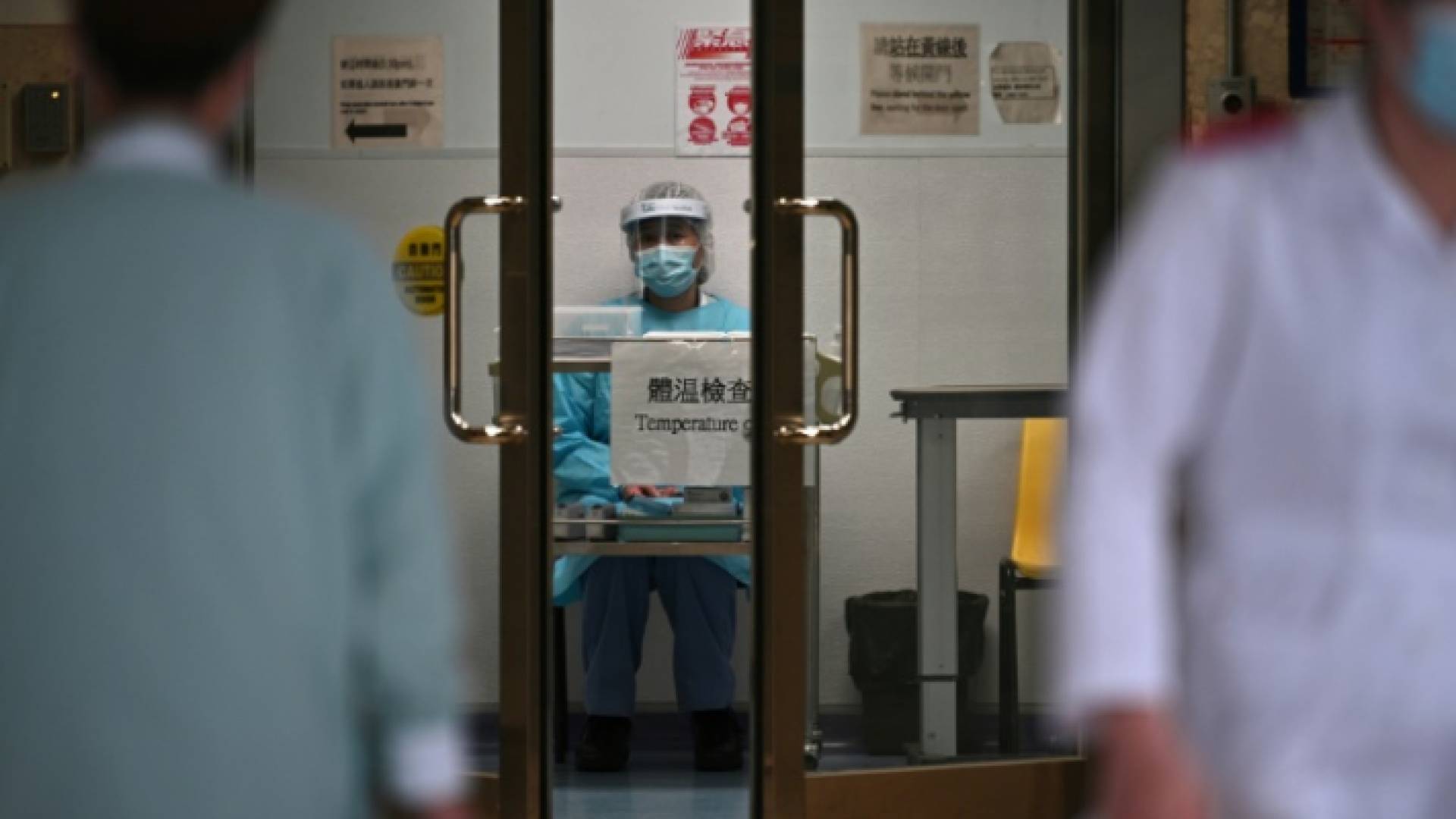 عامل صحي يقوم بفحص حرارة المرضى في مستشفى في هونغ كونغ