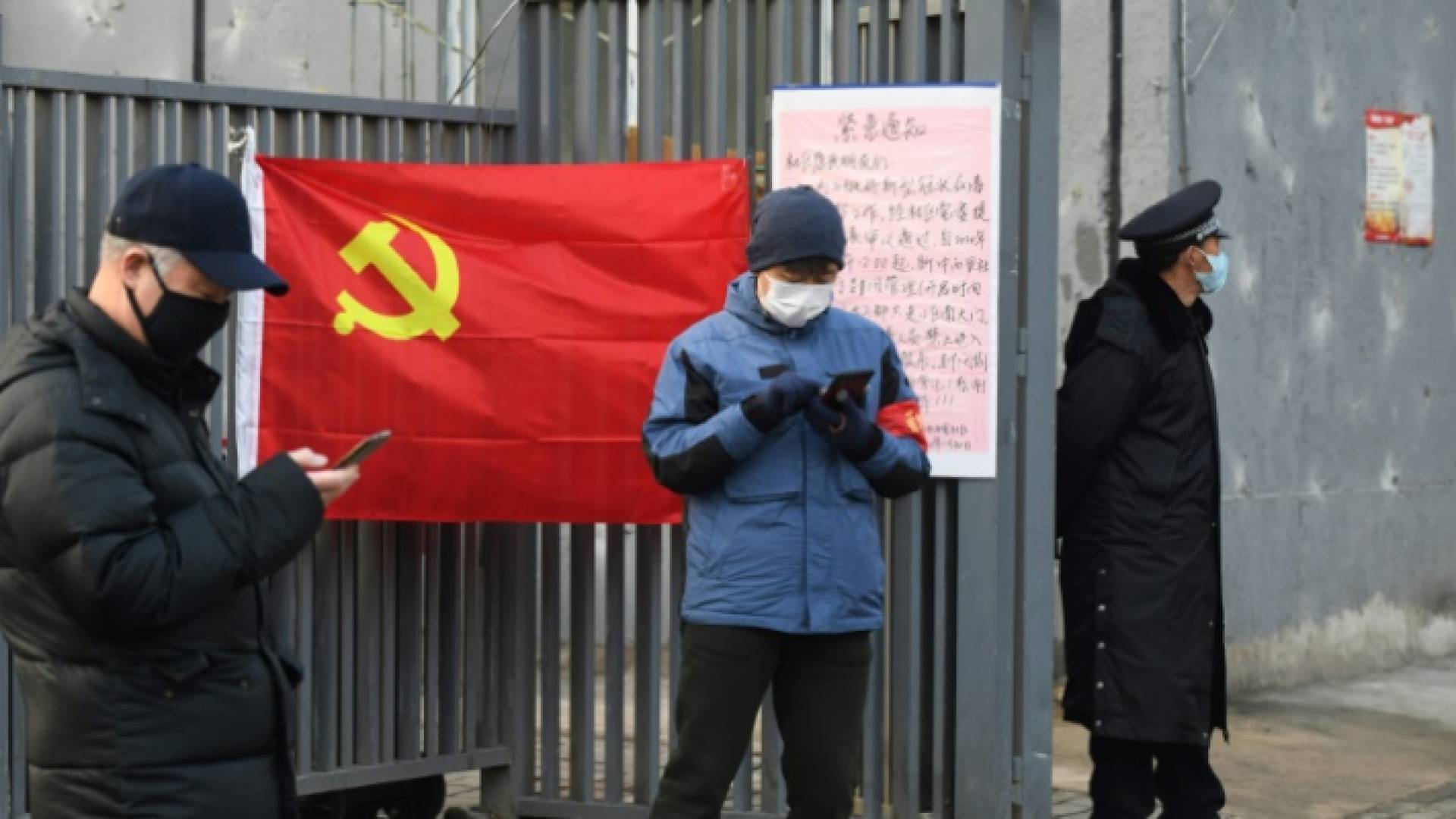 أناس يرتدون الأقنعة للاحتماء من فيروس كورونا المستجد قرب علم الحزب الشيوعي في بكين