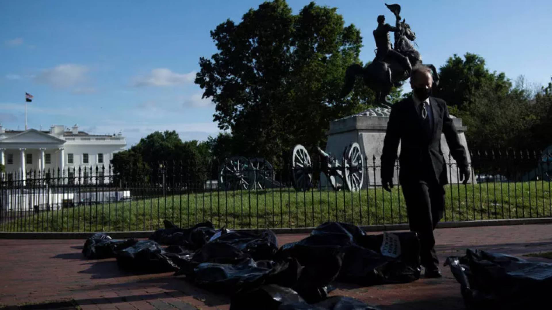 ناشط يسير وسط أكياس تستخدم للف الجثث وضعت أمام البيت الأبيض احتجاجا على طريقة تعامل إدارة ترمب مع أزمة كورونا /ا ف ب