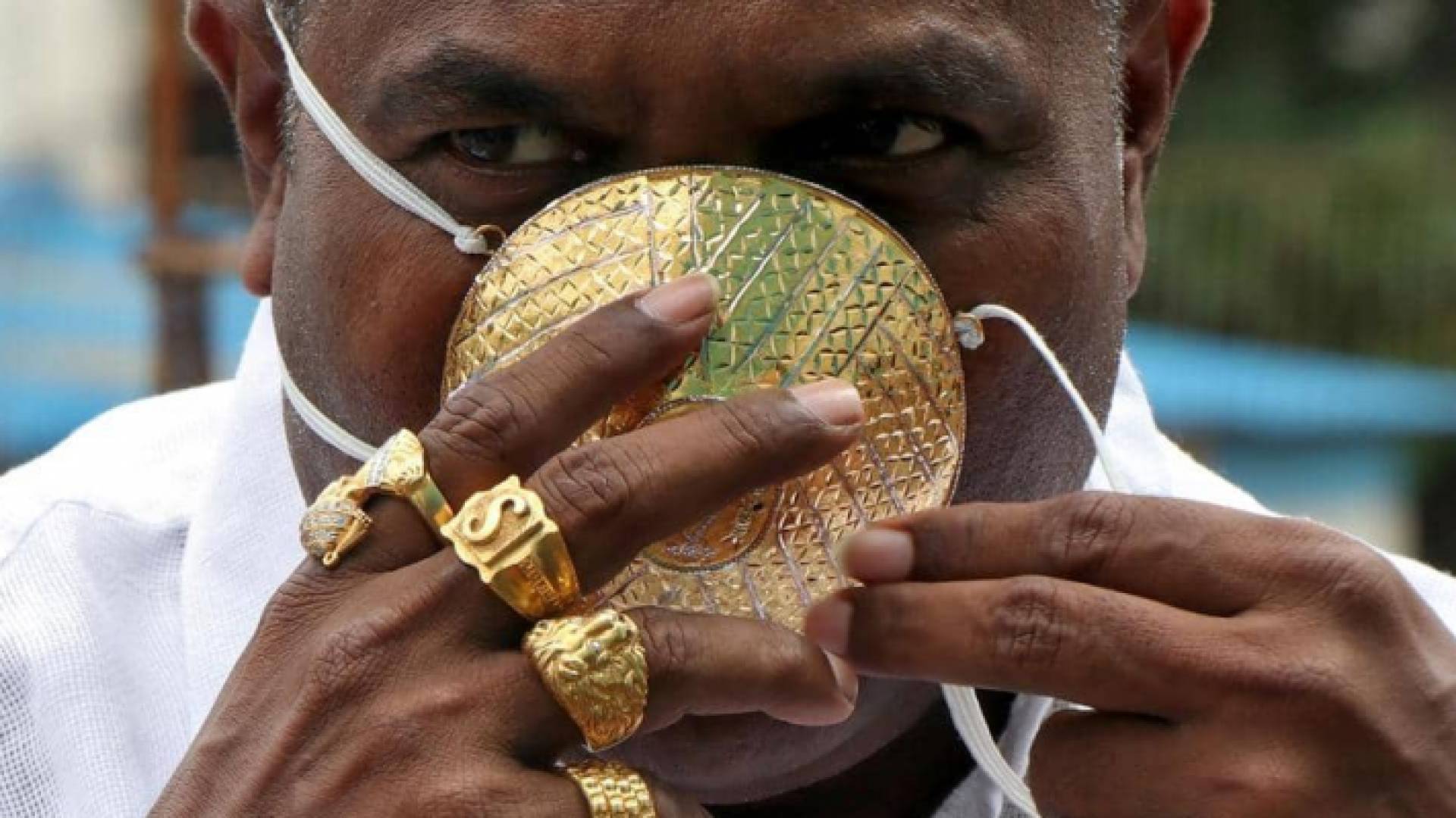 يضع رجل هندي كمامة مصنوعة من الذهب