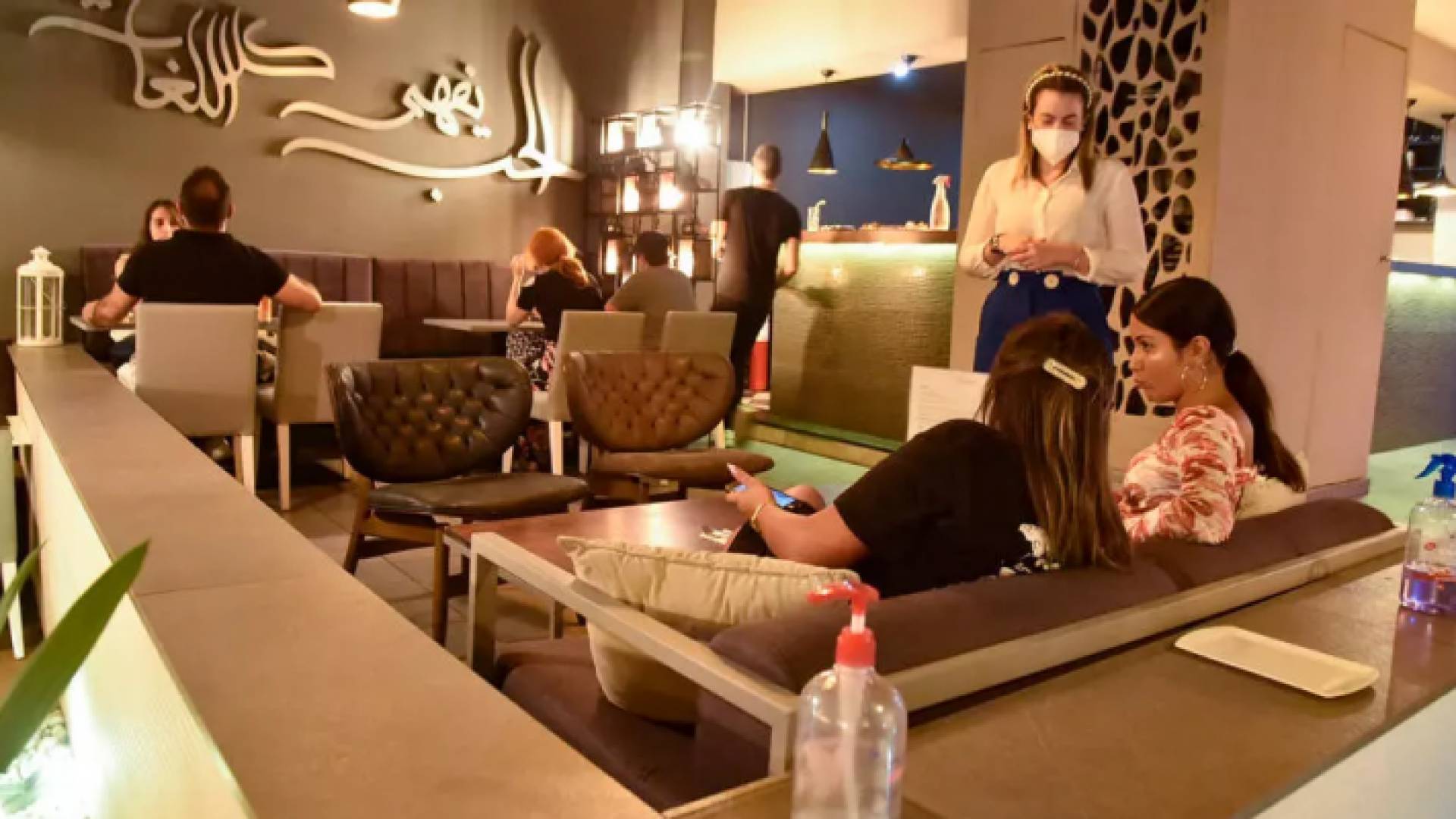 نادلة تضع كمامة خلال خدمتها زبائن في مطعم في الجزائر العاصمة