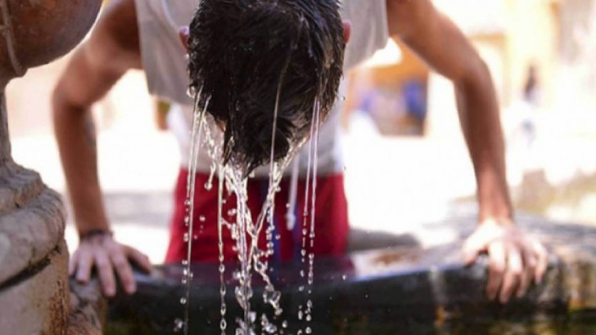 شاب يضع الماء على رأسه للتخفيف من أجواء الحر