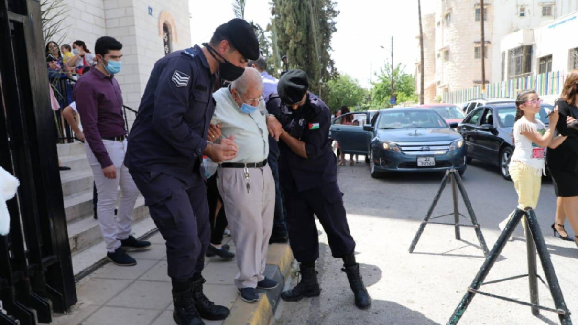 رجلا أمن عام يقومان بمساعدة رجل مسن خلال احتفال المسيحيين بأعياد الفصح المجيدة