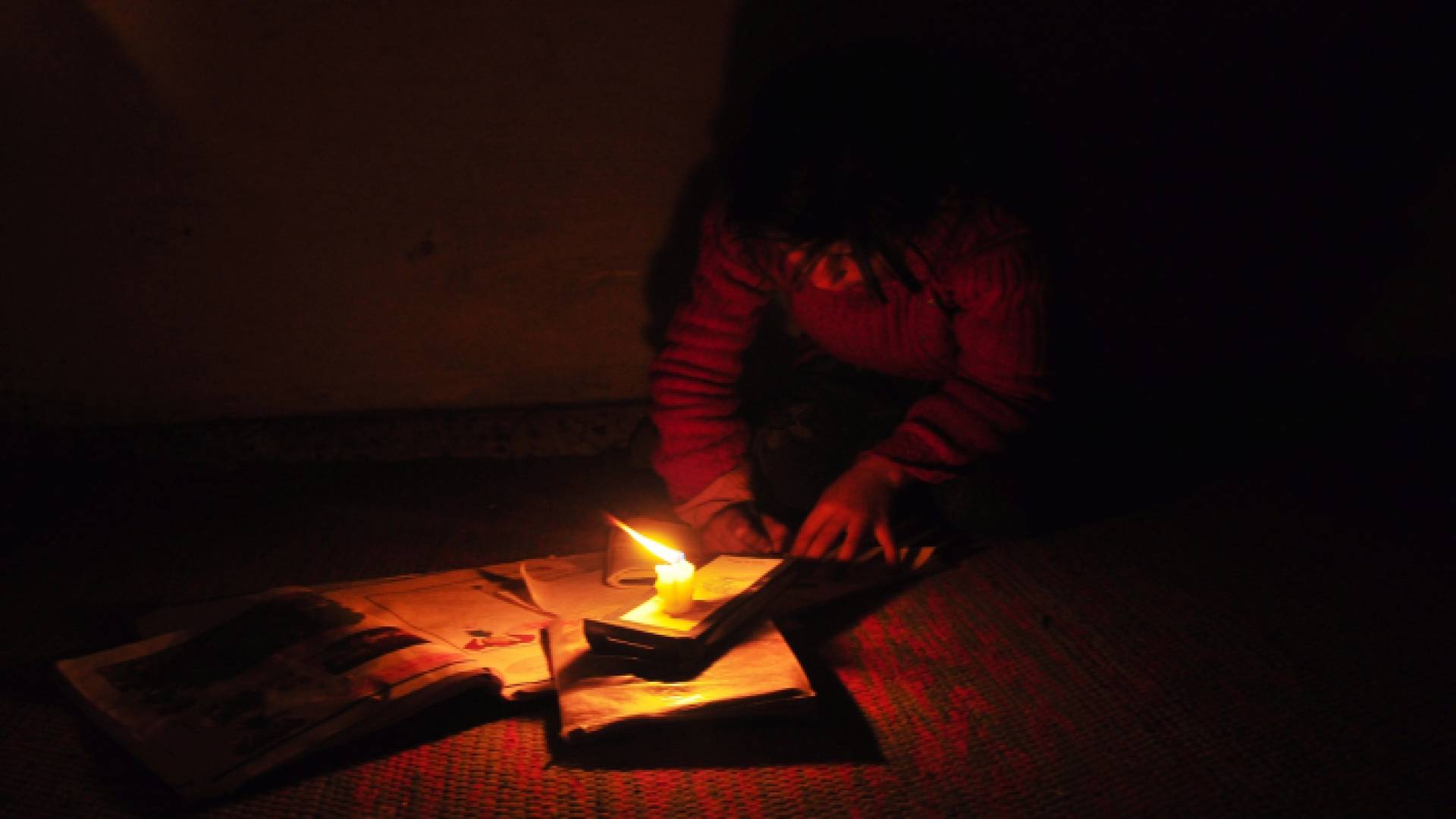 طفلة فلسطينية تكمل دروسها على ضوء الشمعة جراء انقطاع الكهرباء في قطاع غزة