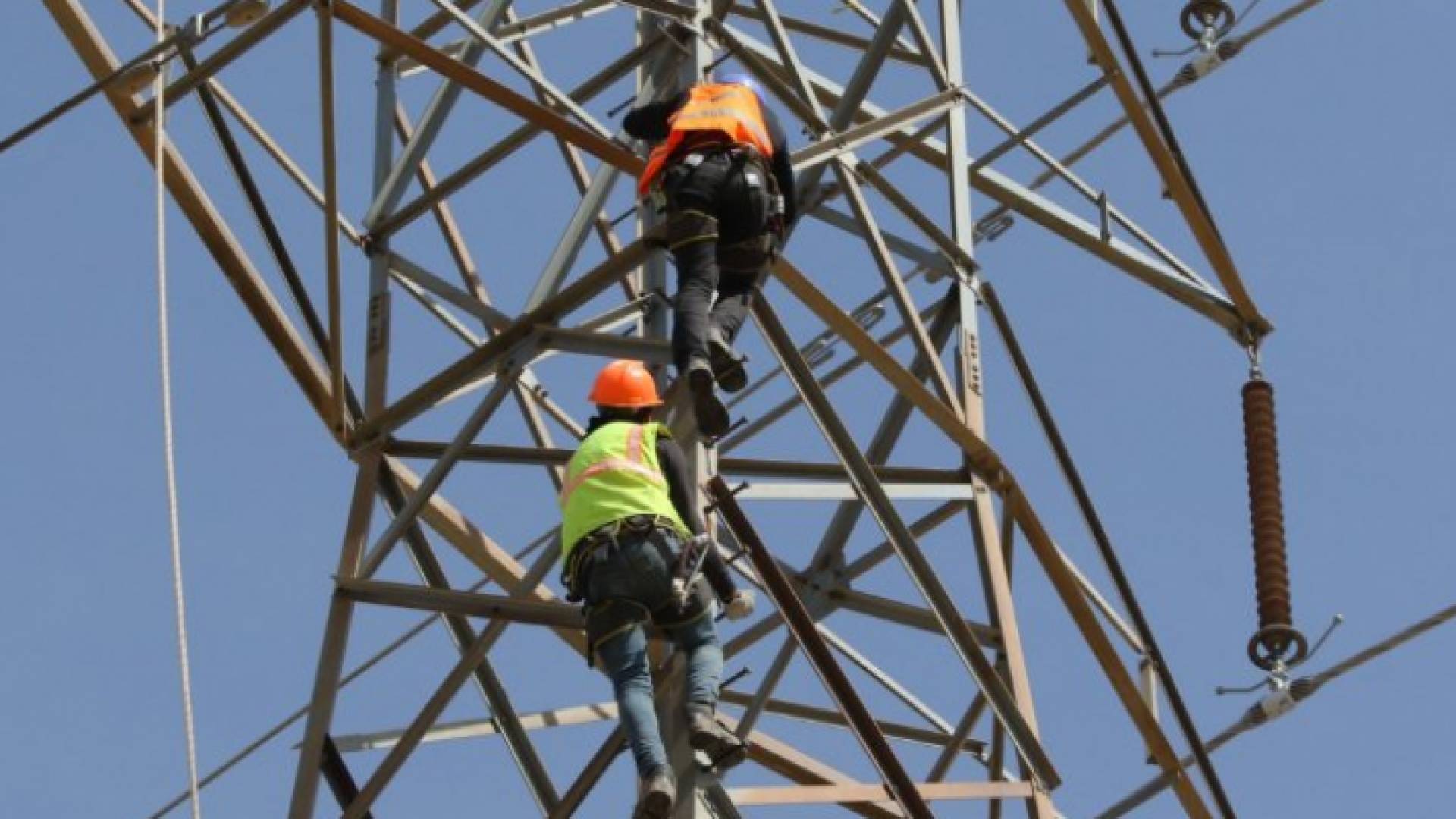 عمال على أحد أبراج الكهرباء يقومون بأعمال صيانة - أرشيفية