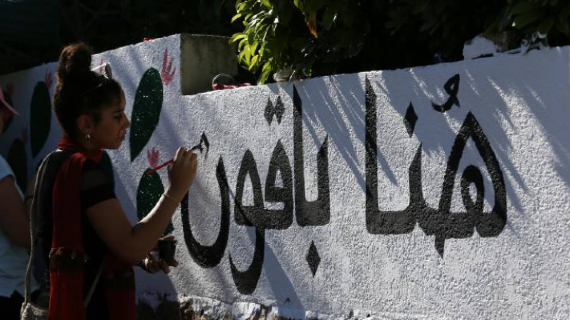 عبارة هنا باقون رسمتها فتاة فلسطينية على أحد جدران حي الشيخ جراح في القدس المحتلة
