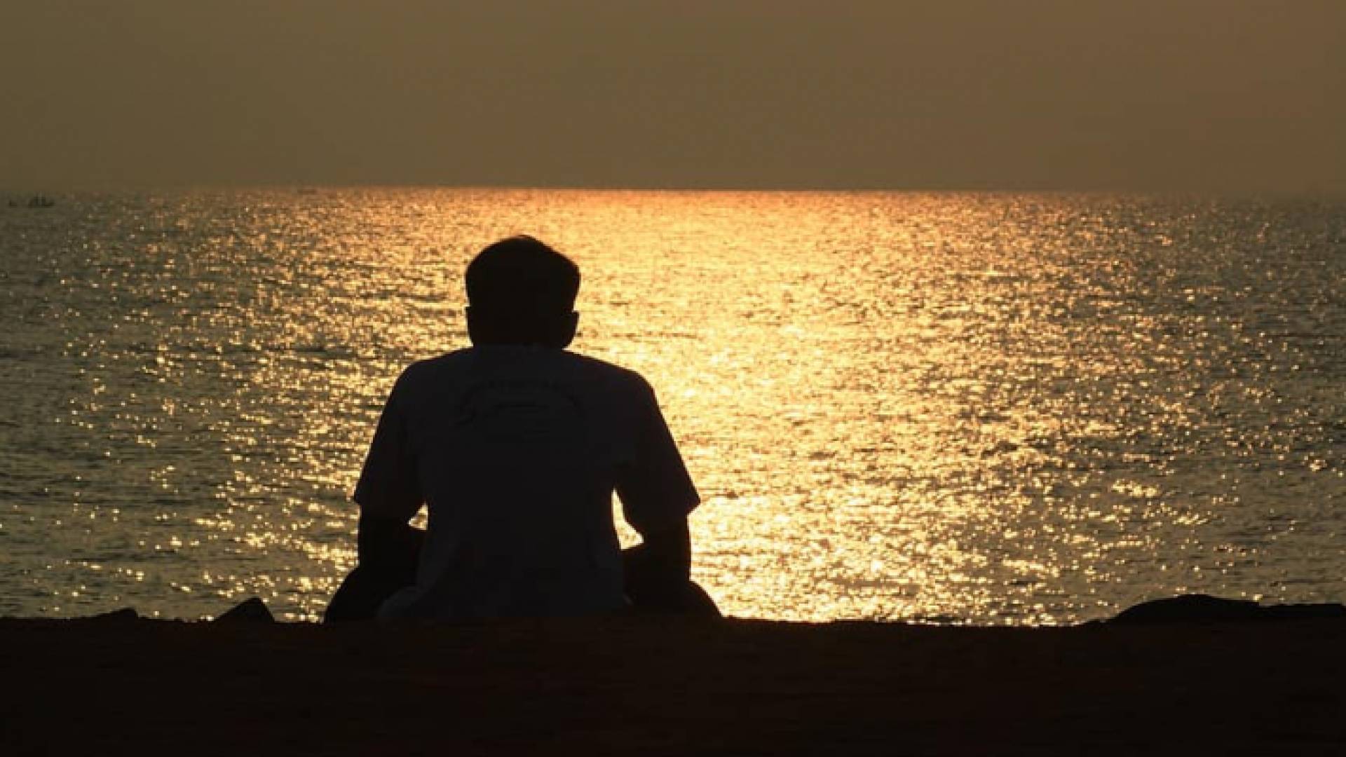 شخص يجلس وحيدا على شاطئ البحر - تعبيرية