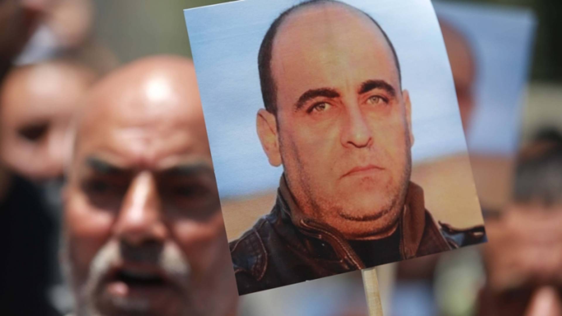 متظاهر فلسطيني يرفع صورة نزار بنات