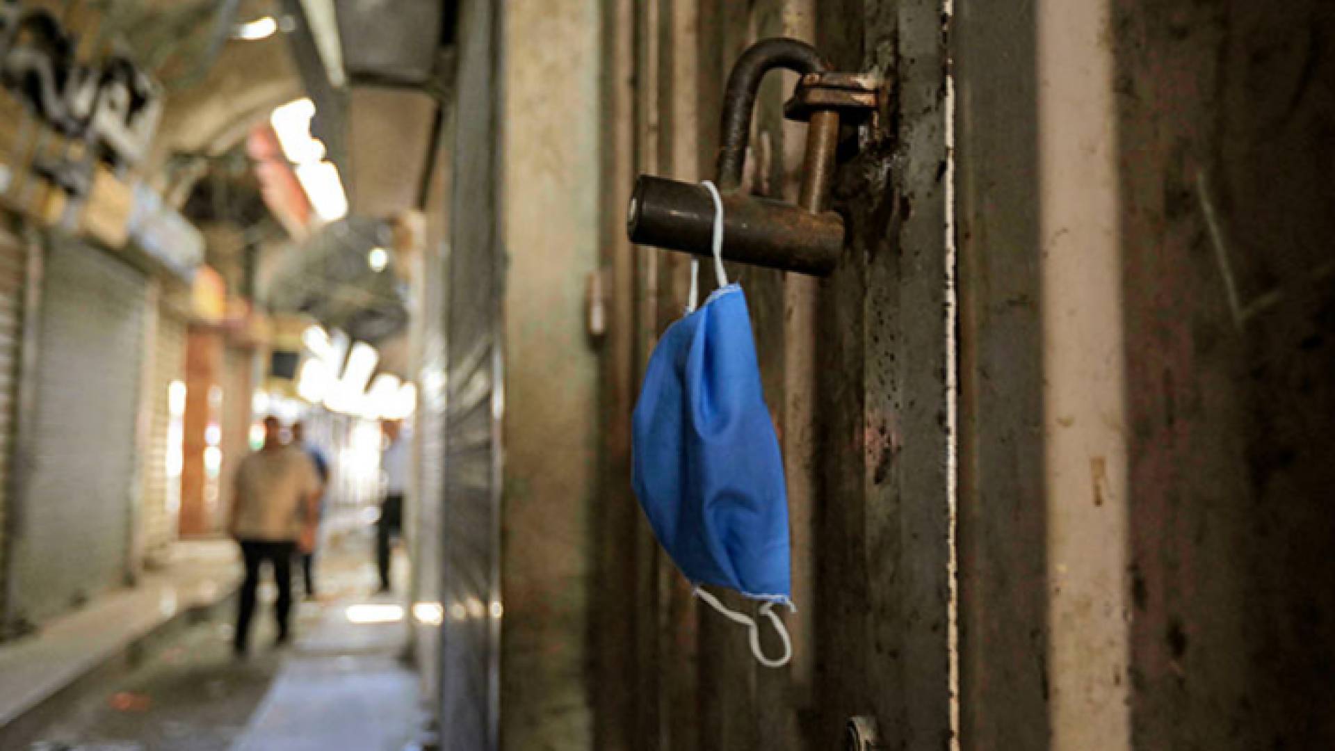 كمامة معلقة على باب أحد المحلات التجارية في قطاع غزة