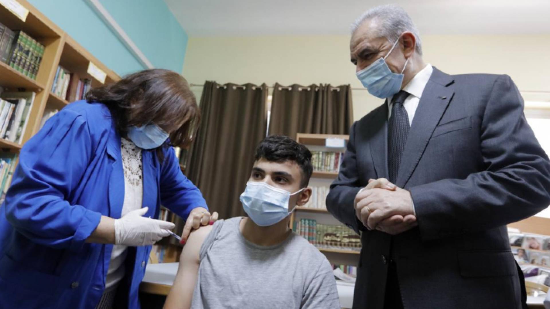 رئيس الوزراء الفلسطيني محمد اشتية في أثناء مشاركته في حملة تطعيم طلبة المدارس من فيروس كورونا في رام الله