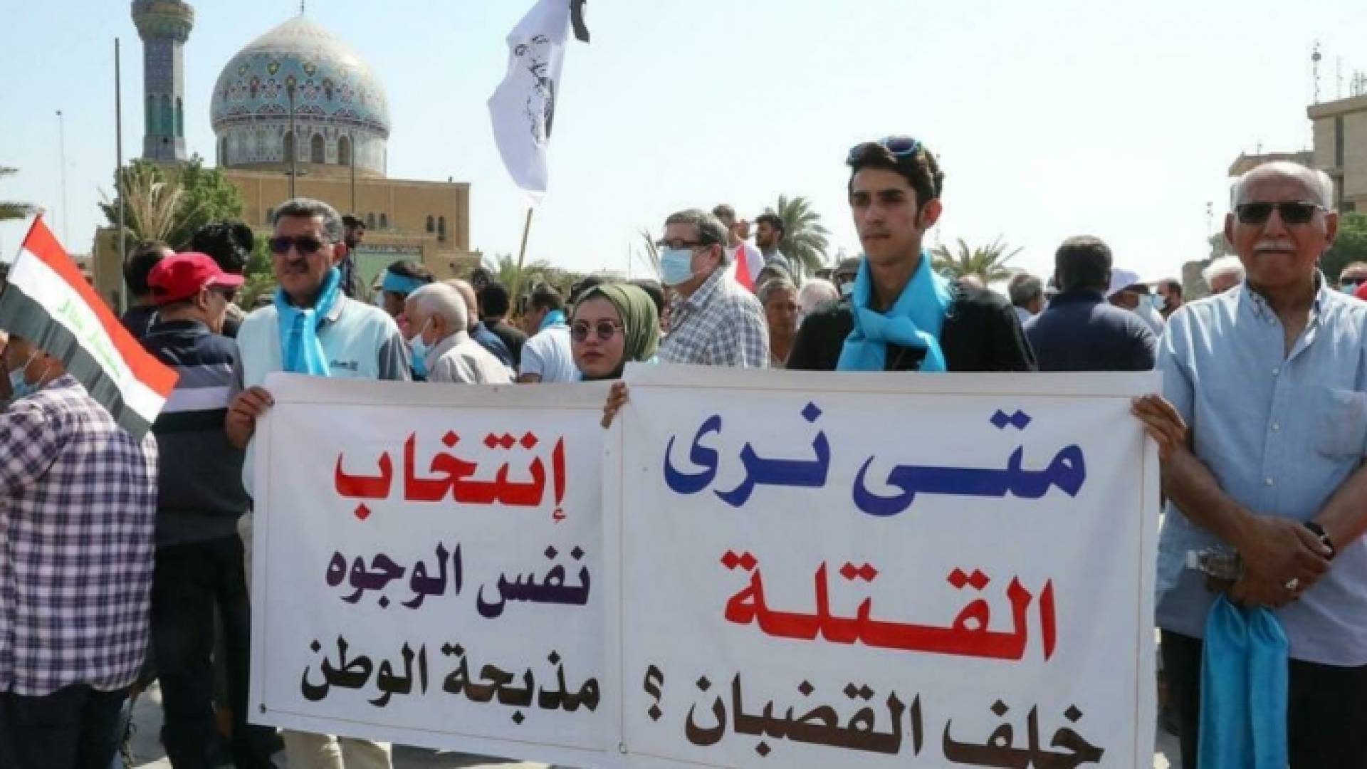 عراقيون يرفعون لافتات أثناء تجمعهم في ساحة الفردوس وسط بغداد
