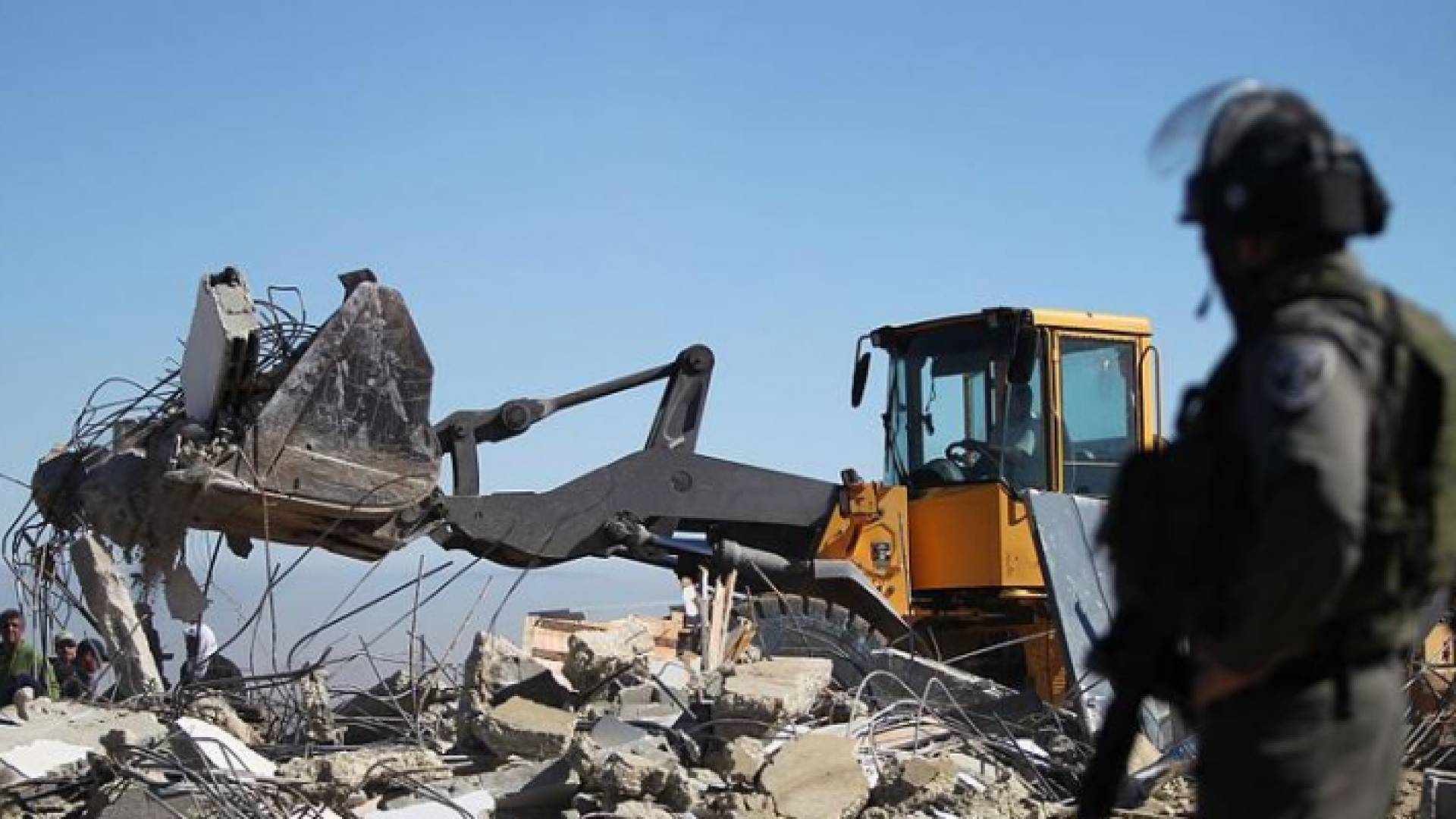 جندي تابع لقوات الاحتلال يقف أمام جرافة تهدم منزل مواطن فلسطيني - أرشيفية