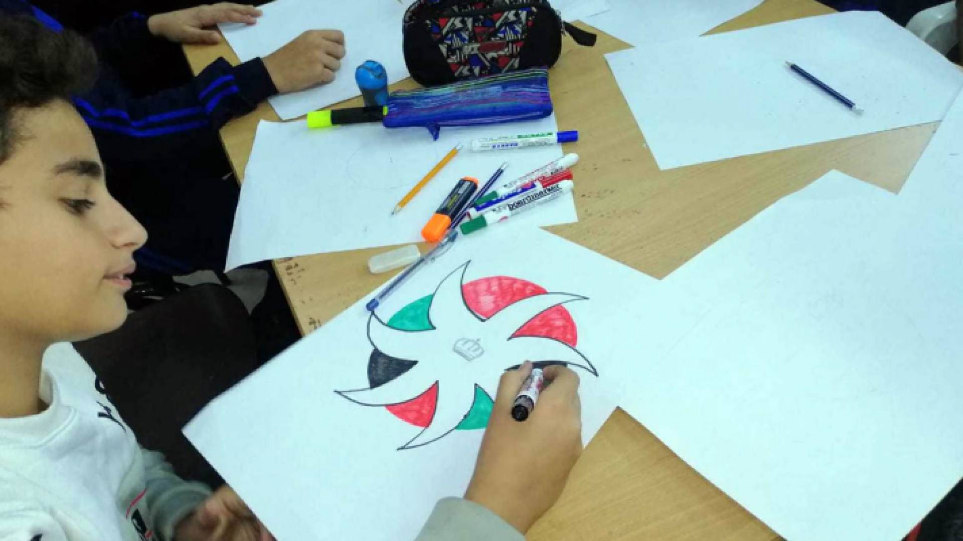 طفل يرسم شعار مباردة حقق