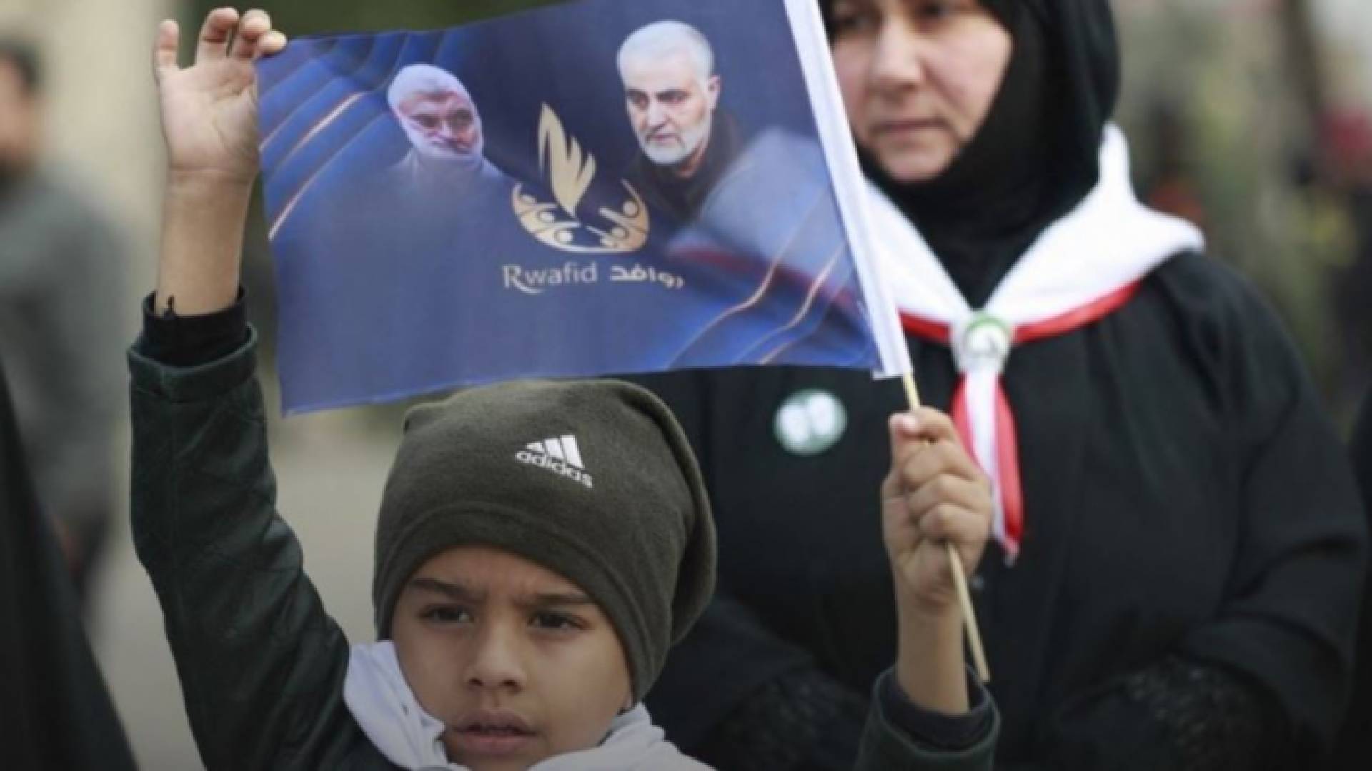 طفل عراقي يرفع صورة لسليماني والمهندس في بغداد (أ ف ب)