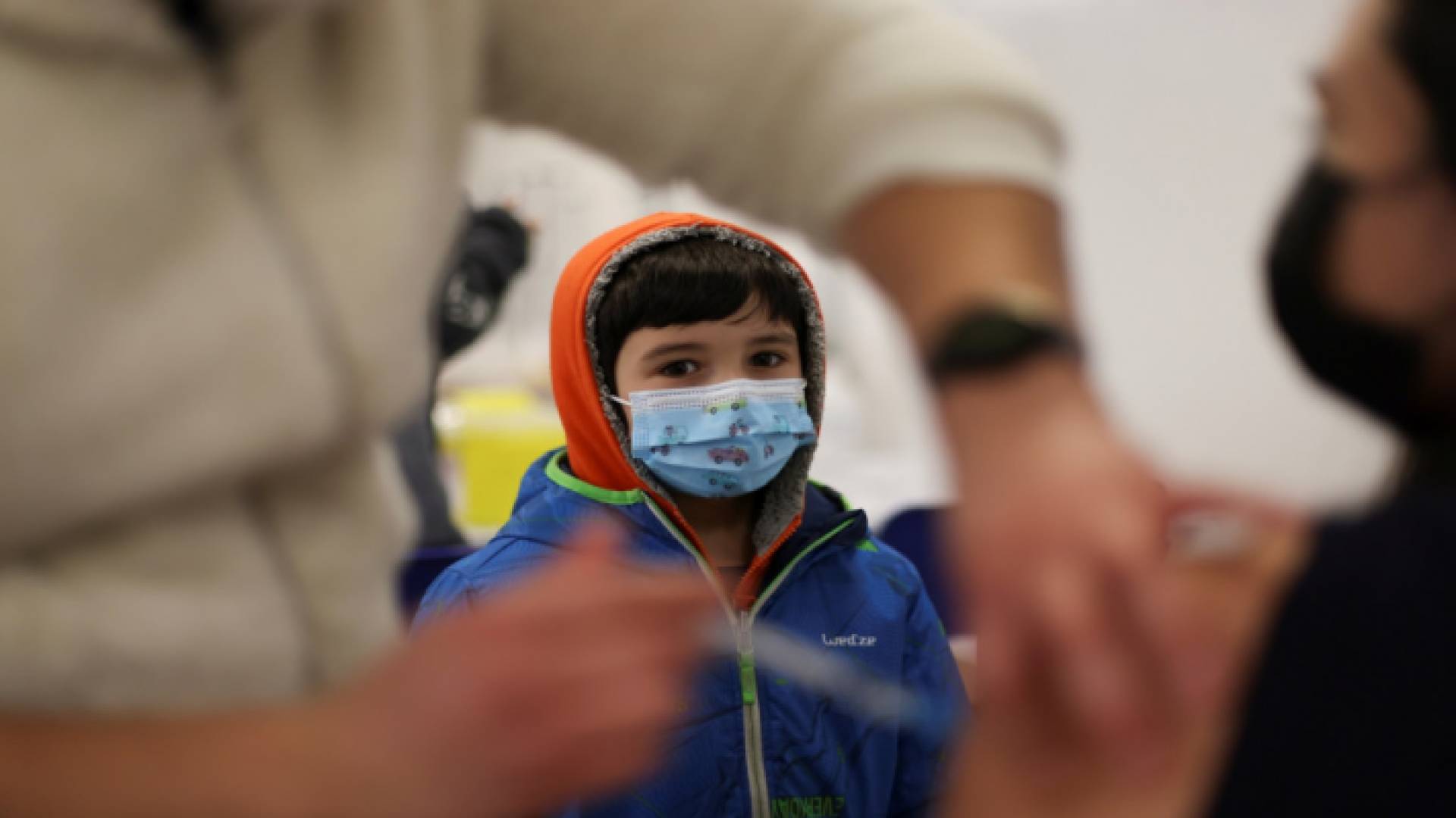 طفل ينظر إلى سيدة تتلقى اللقاح