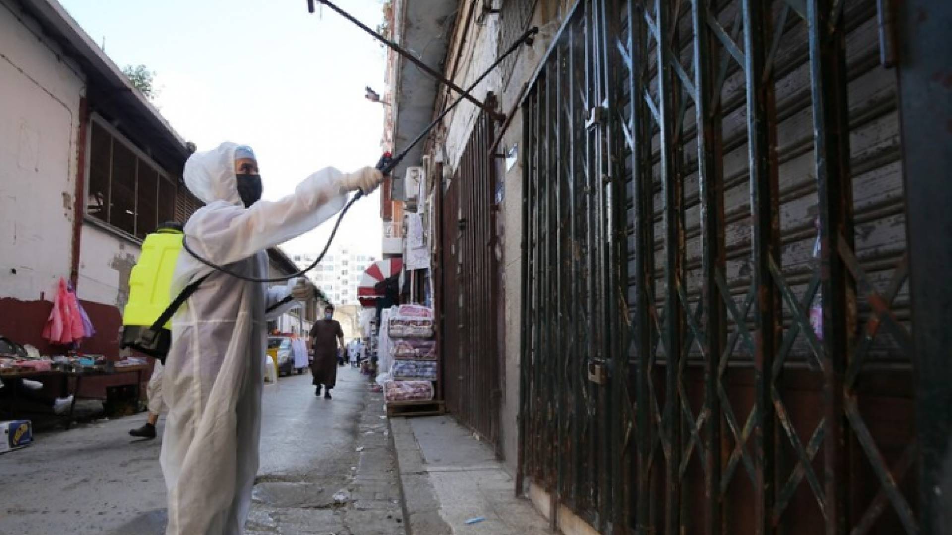عامل في القطاع الصحي الجزائري يعقم أبواب المحال التجارية - أرشيفية