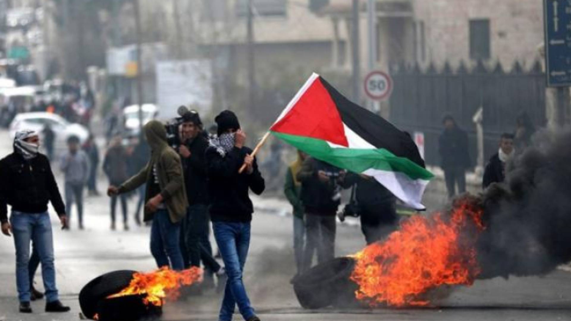 شاب يحمل العلم الفلسطيني في مواجهات سابقة مع قوات الاحتلال - أرشيفية