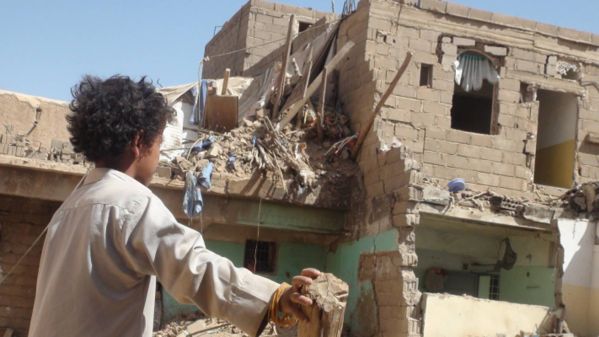 طفل يمني ينظر إلى منزل ذويه المنهار