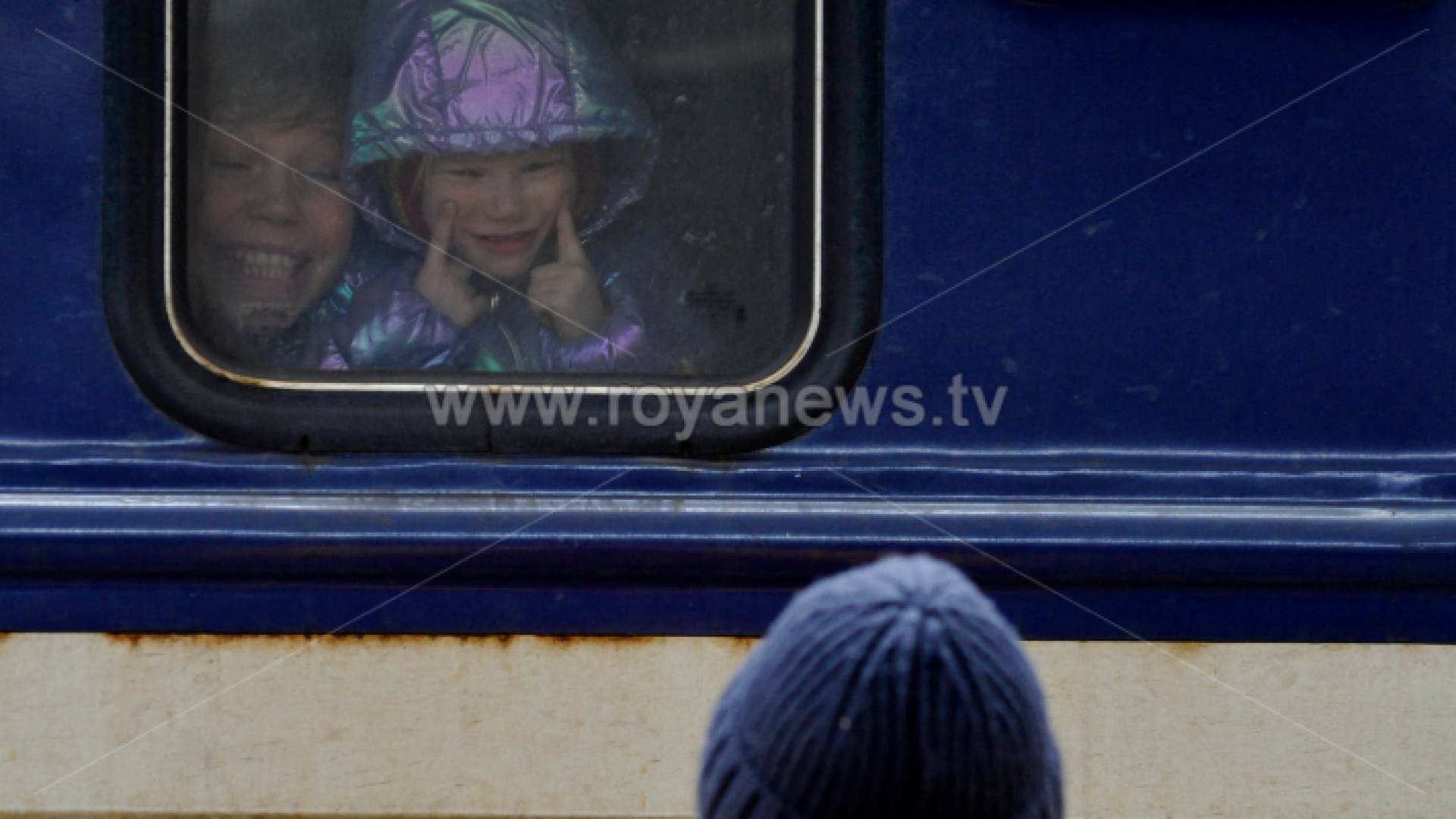 فتاة في قطار إجلاء ترسم وجوهًا لرجل يقيم على الرصيف في محطة القطار المركزية في كييف