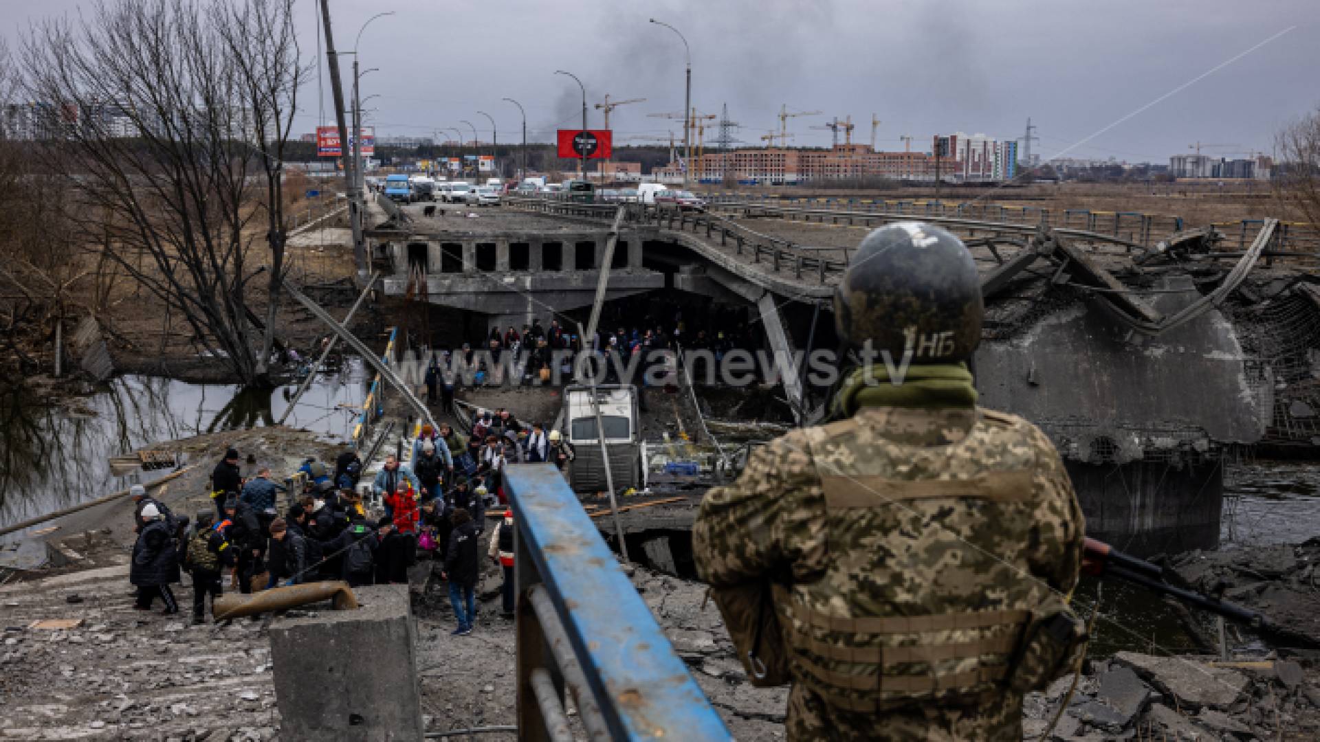 جندي أوكراني ينظر بينما يعبر الأشخاص الذين تم إجلاؤهم جسرًا مدمرًا أثناء فرارهم من مدينة إيربين ، شمال غرب كييف