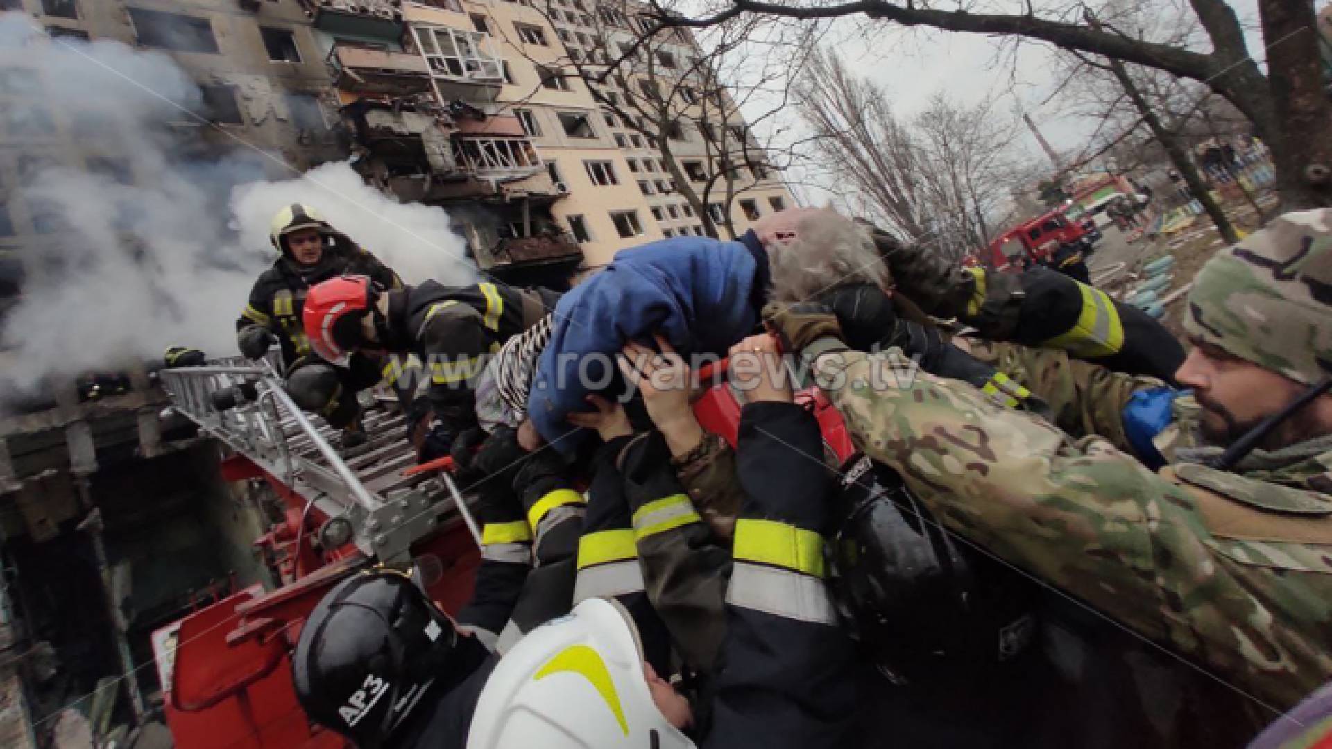 يقوم رجال الإطفاء بإخلاء شخص اوكراني من مبنى سكني تعرض للقصف في منطقة أوبولون في كييف