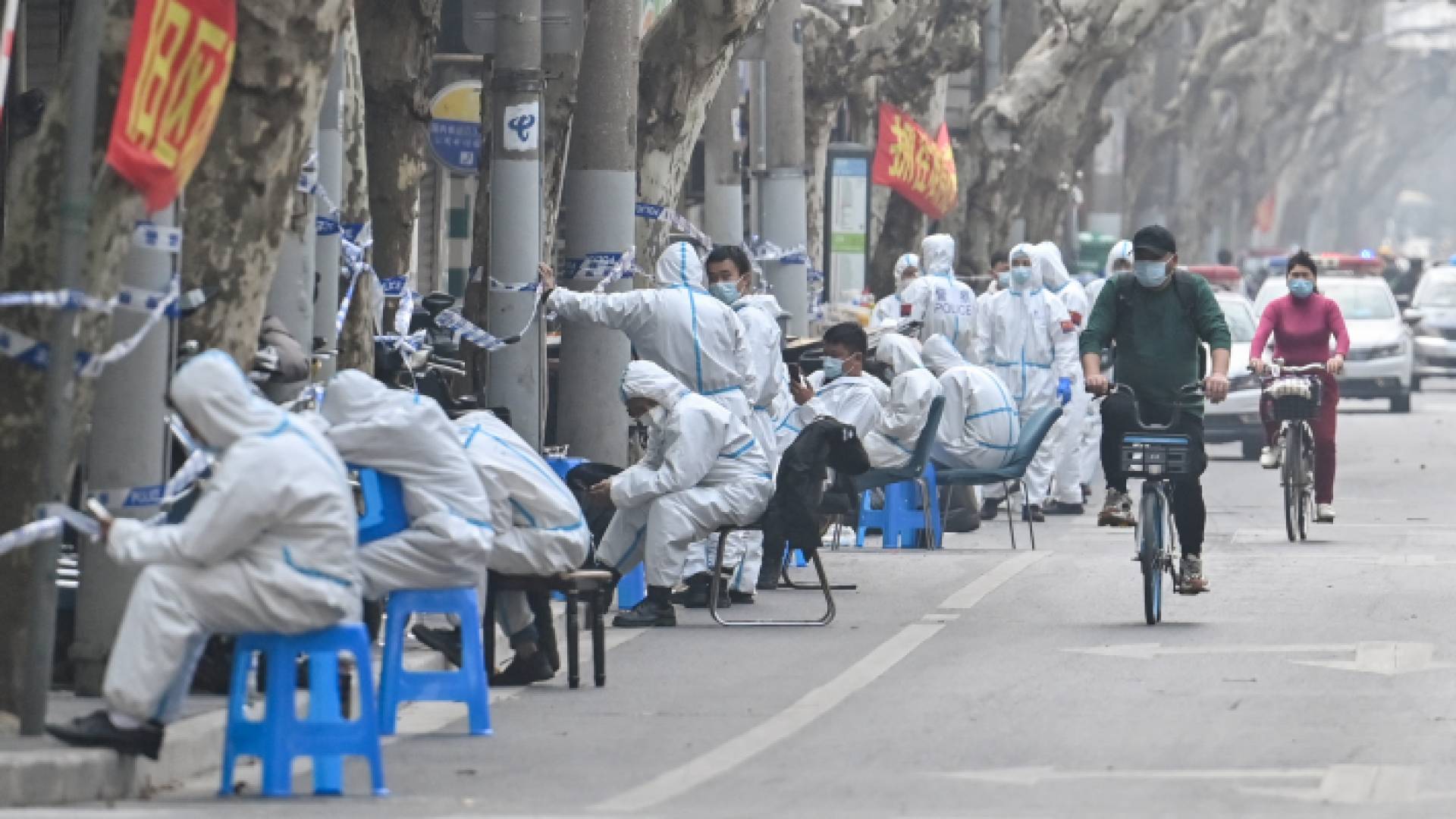 عمال يرتدون ملابس واقية بجوار بعض مناطق الإغلاق بعد اكتشاف حالات جديدة من COVID-19 في شنغهاي - AFP