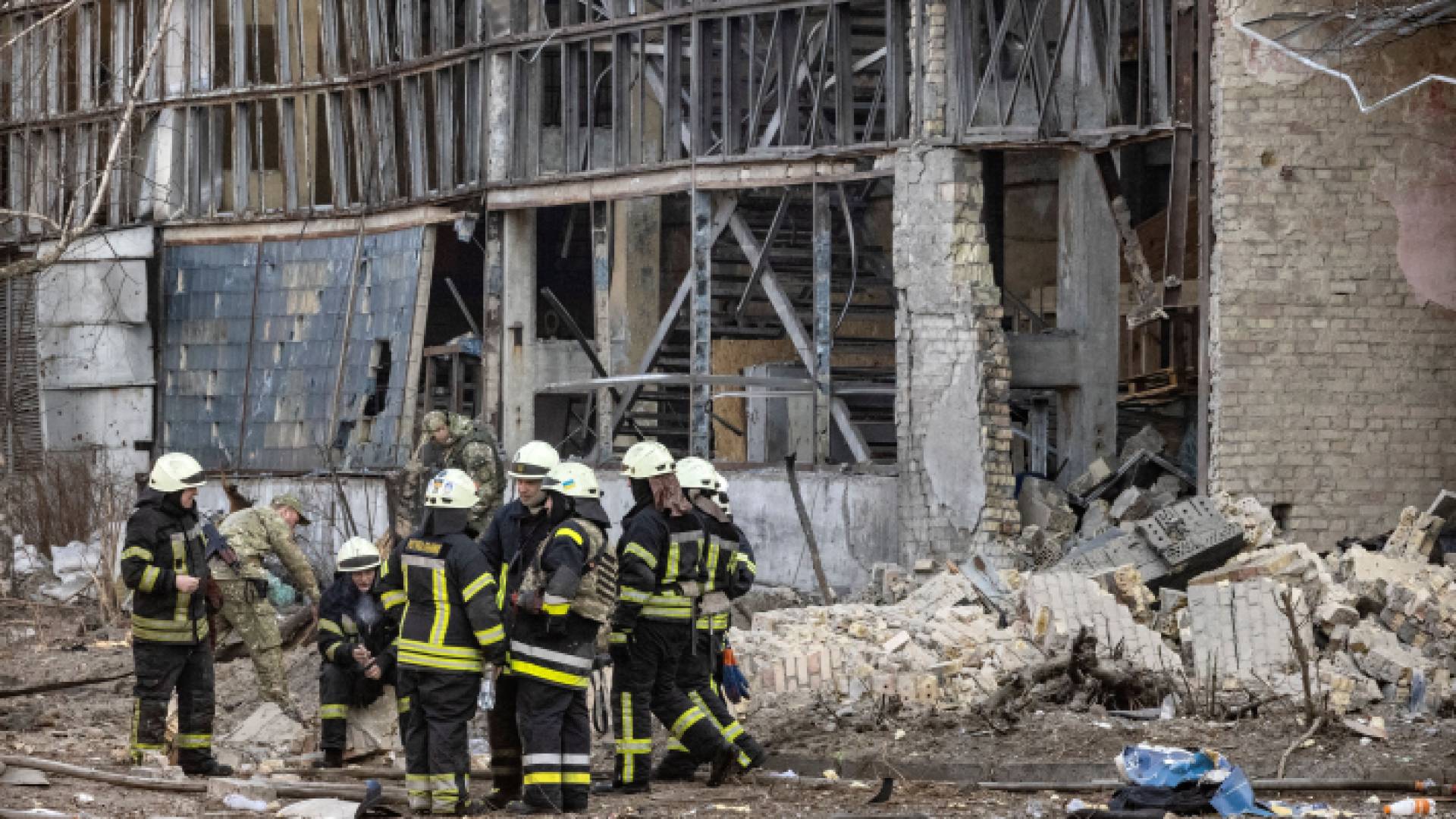 رجال إطفاء يقفون أمام مبنى تعرف للقصف في كييف