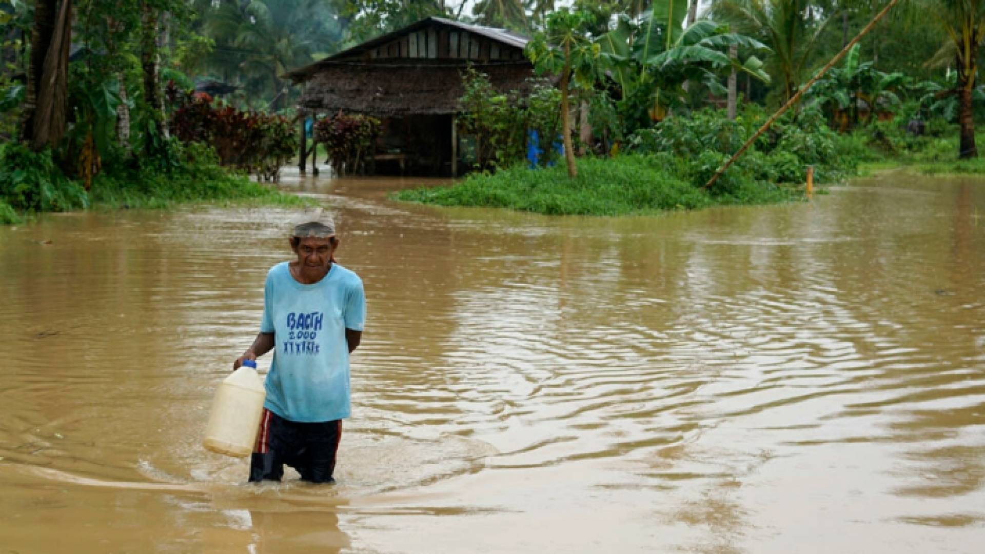 رجل يمشي على طريق غمرته المياه قرب منزله في بلدة أبويوغ في منطقة ليتي في جنوب الفيليبين