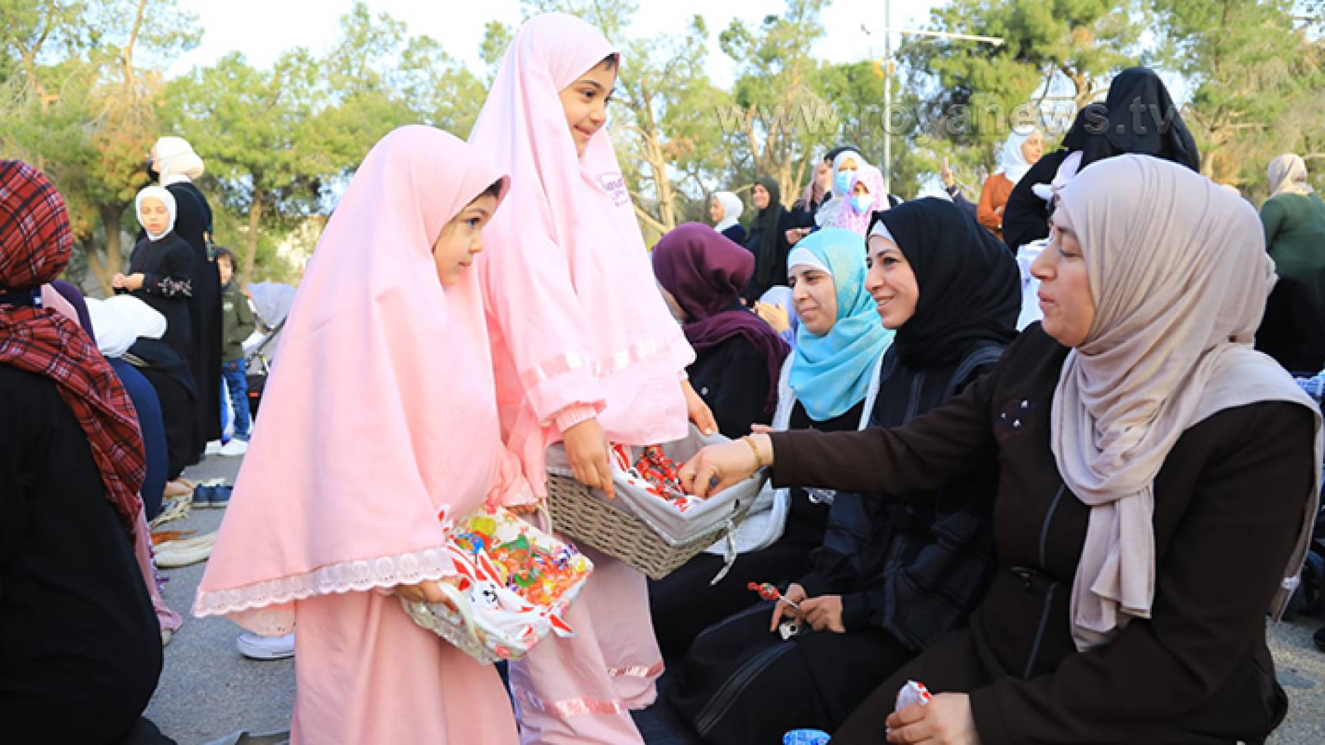 طفلتان توزعان الحلوى في أحد المصليات فرحا بالعيد
