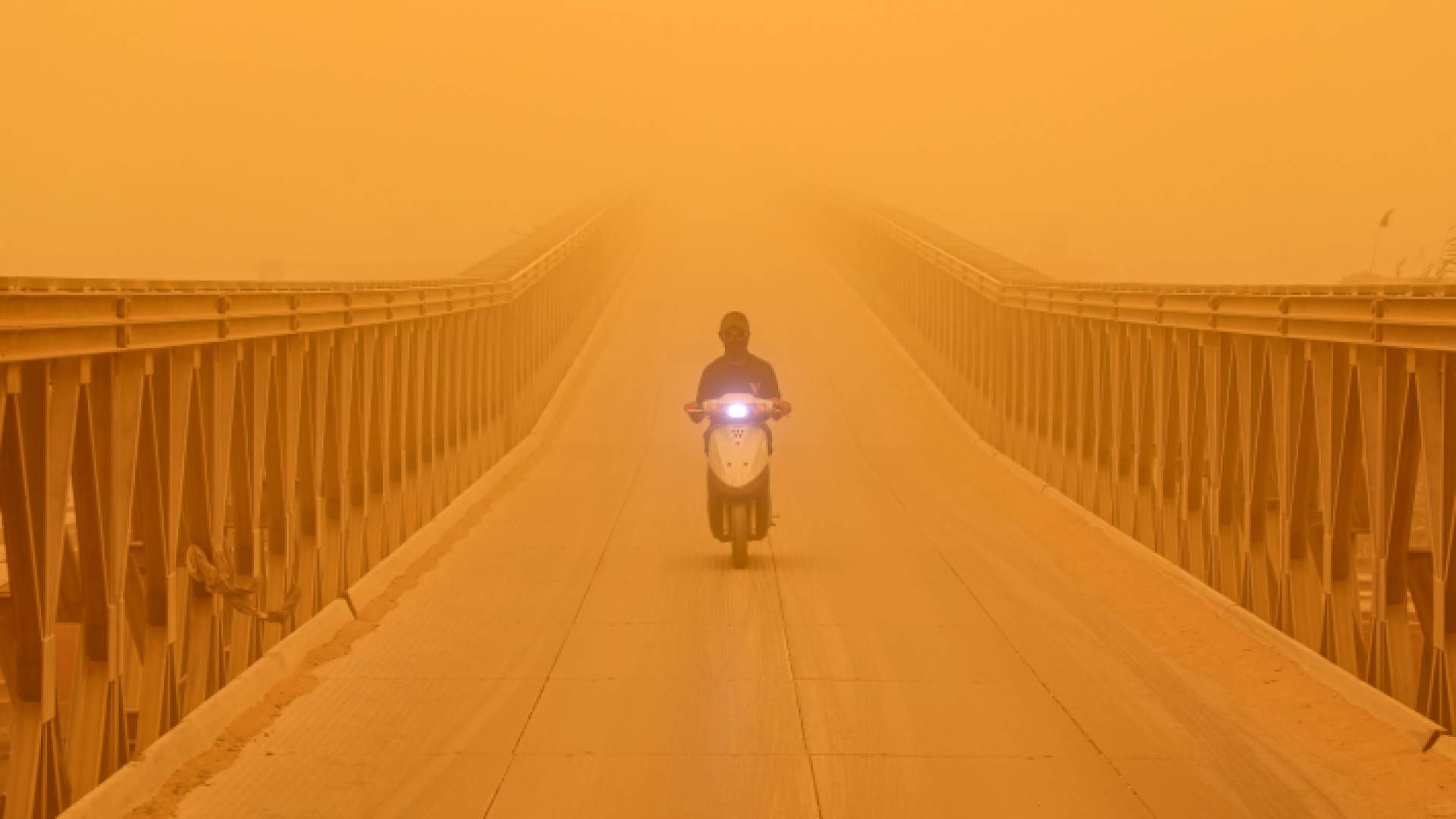 رجل يقود دراجته على جسر للمشاة فوق نهر الفرات