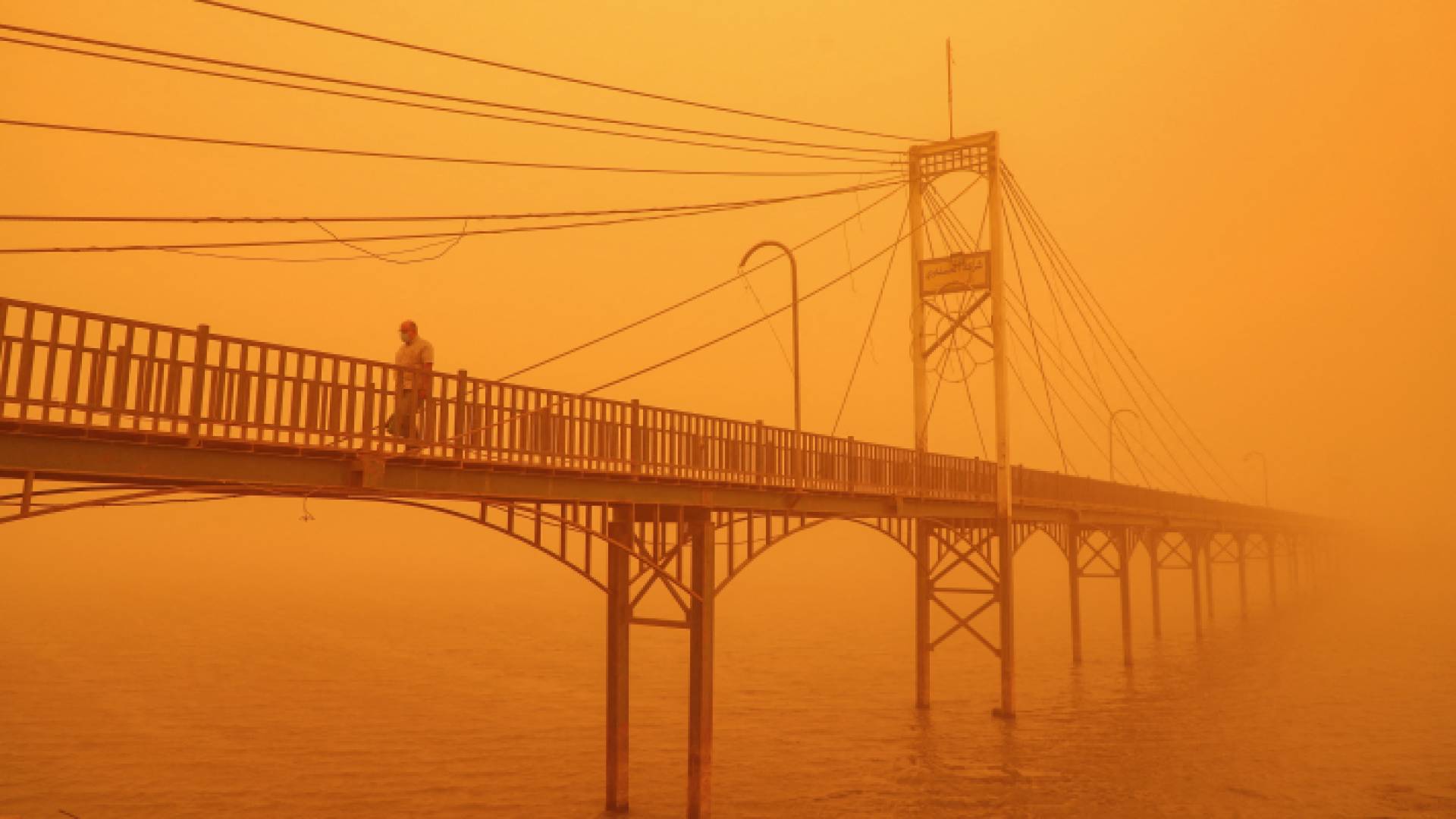 رجل يسير على الجسر وسط العاصفة الترابية