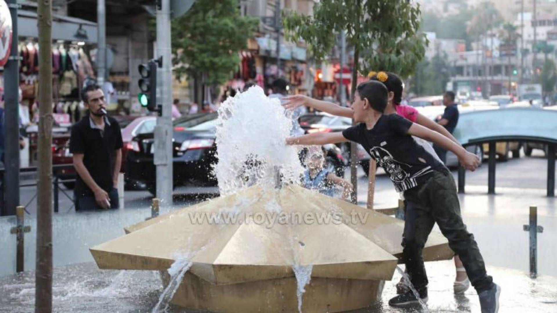 طفلان يداعبان نافورة مياه في منطقة وسط البلد
