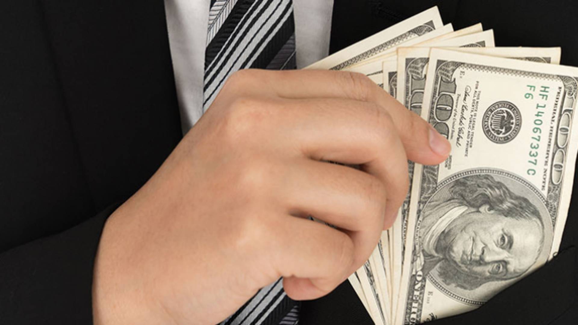 صورة تعبيرية لشخص يحمل دولارات