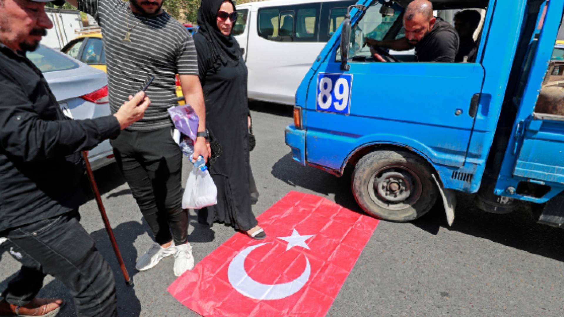 متظاهرون عراقيون يقفون على العلم الوطني التركي خارج مكتب التأشيرات التركية في بغداد في 21 يوليو / تموز 2022 خلال مظاهرة ضد الهجوم