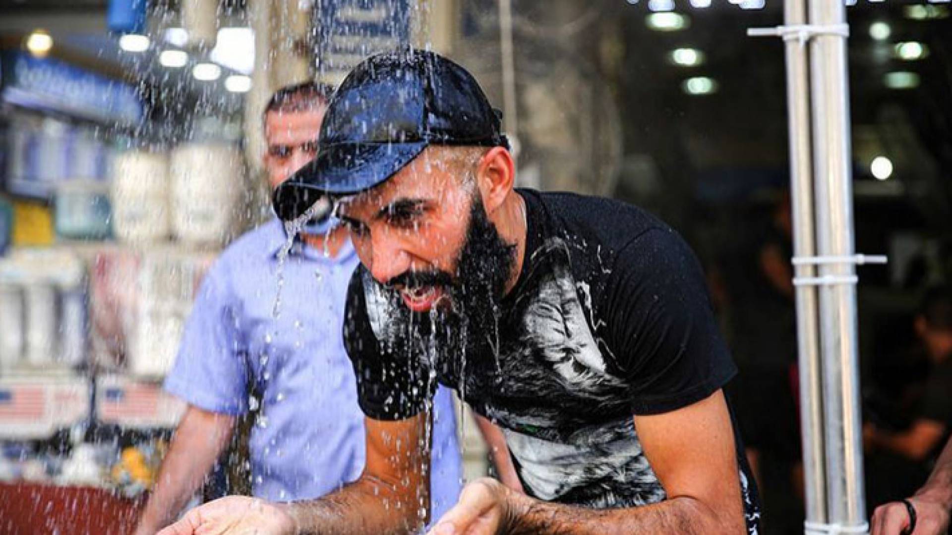 شاب يغتسل بالماء نتيجة ارتفاع درجات الحرارة