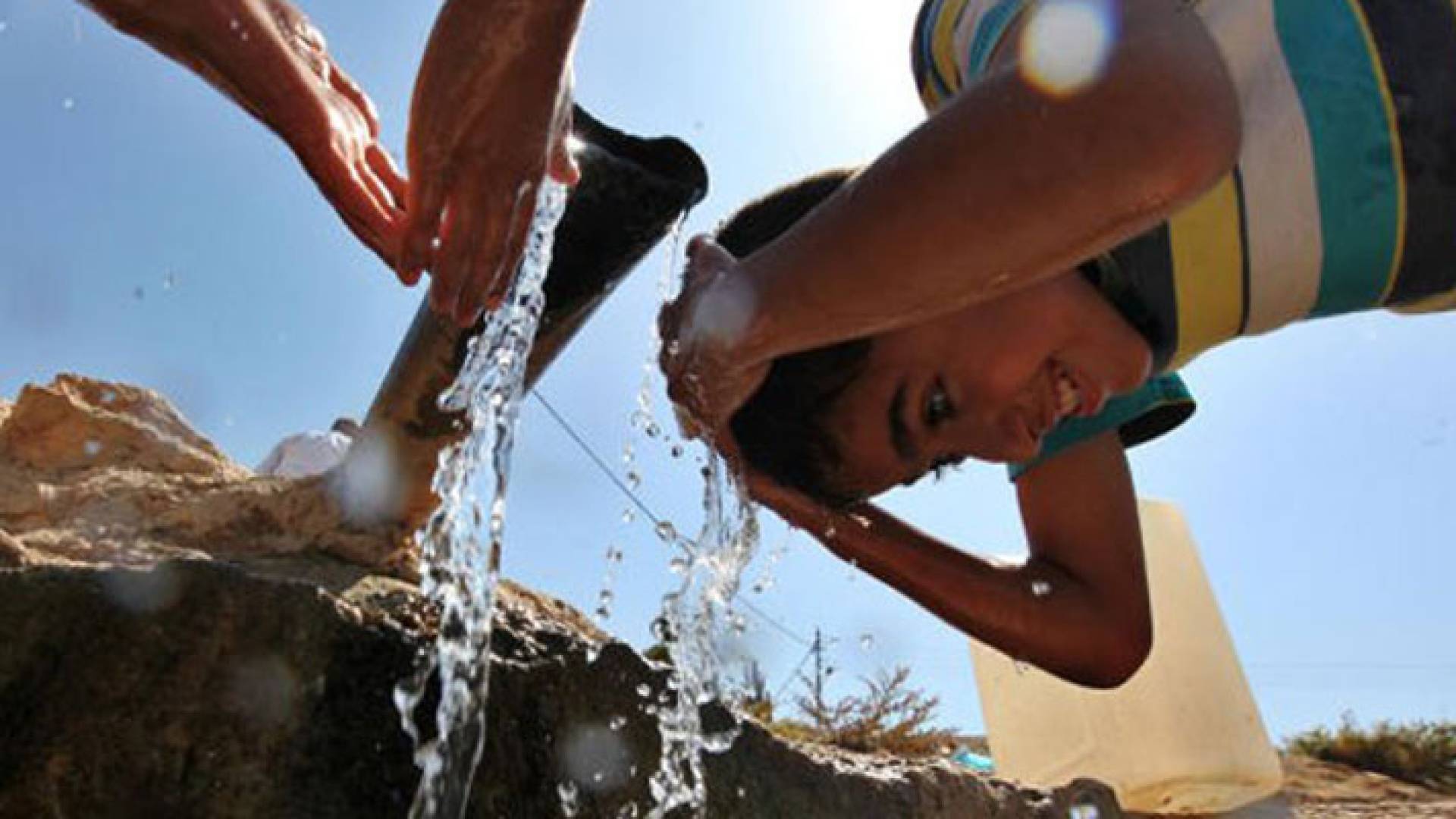 طفل يسكب الماء على راسه جراء تأثره بدرجات الحرارة المرتفعة