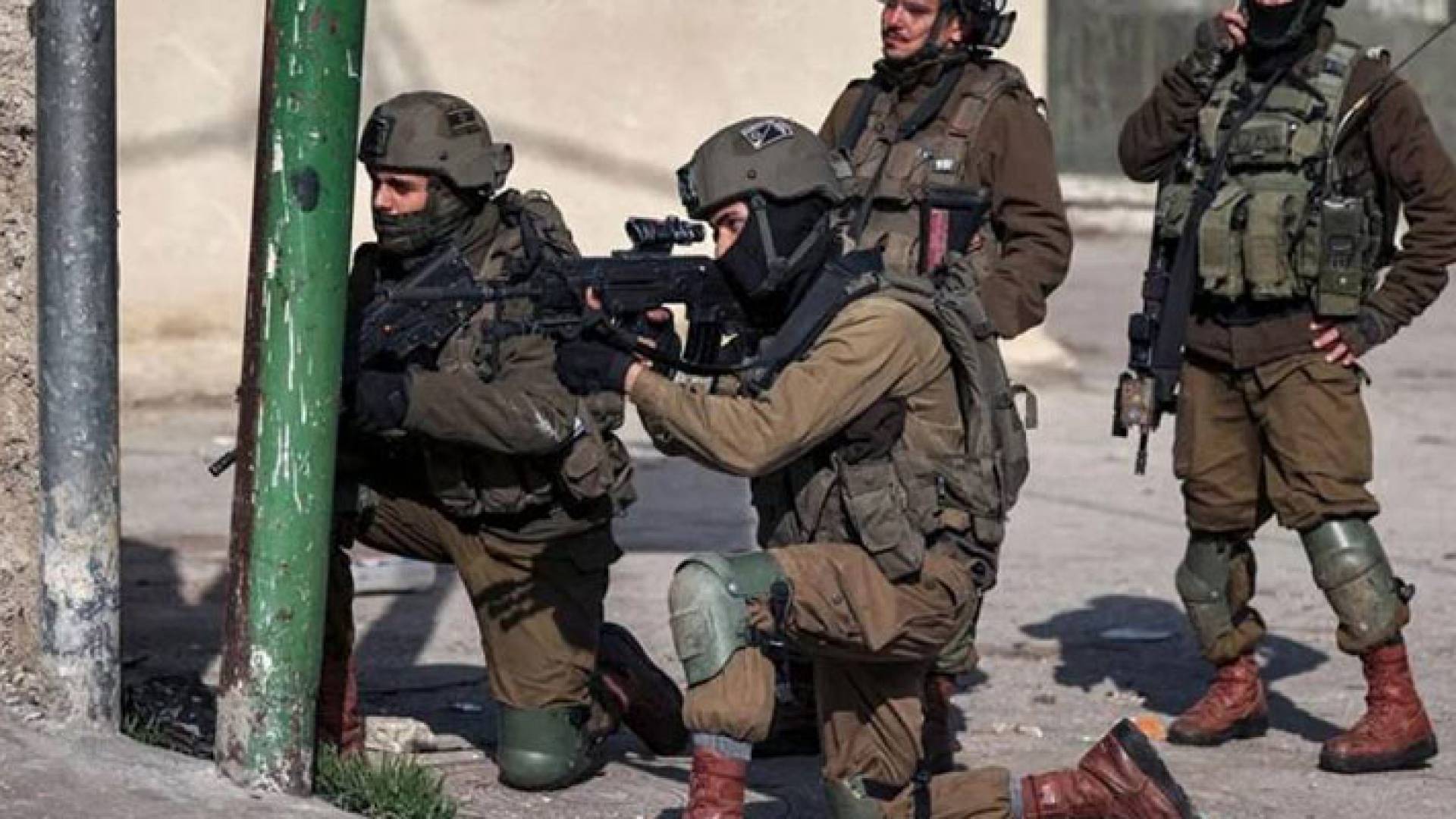 جندي إسرائيلي متأهب لتوجيه رصاص بندقيته نحو فلسطينيين