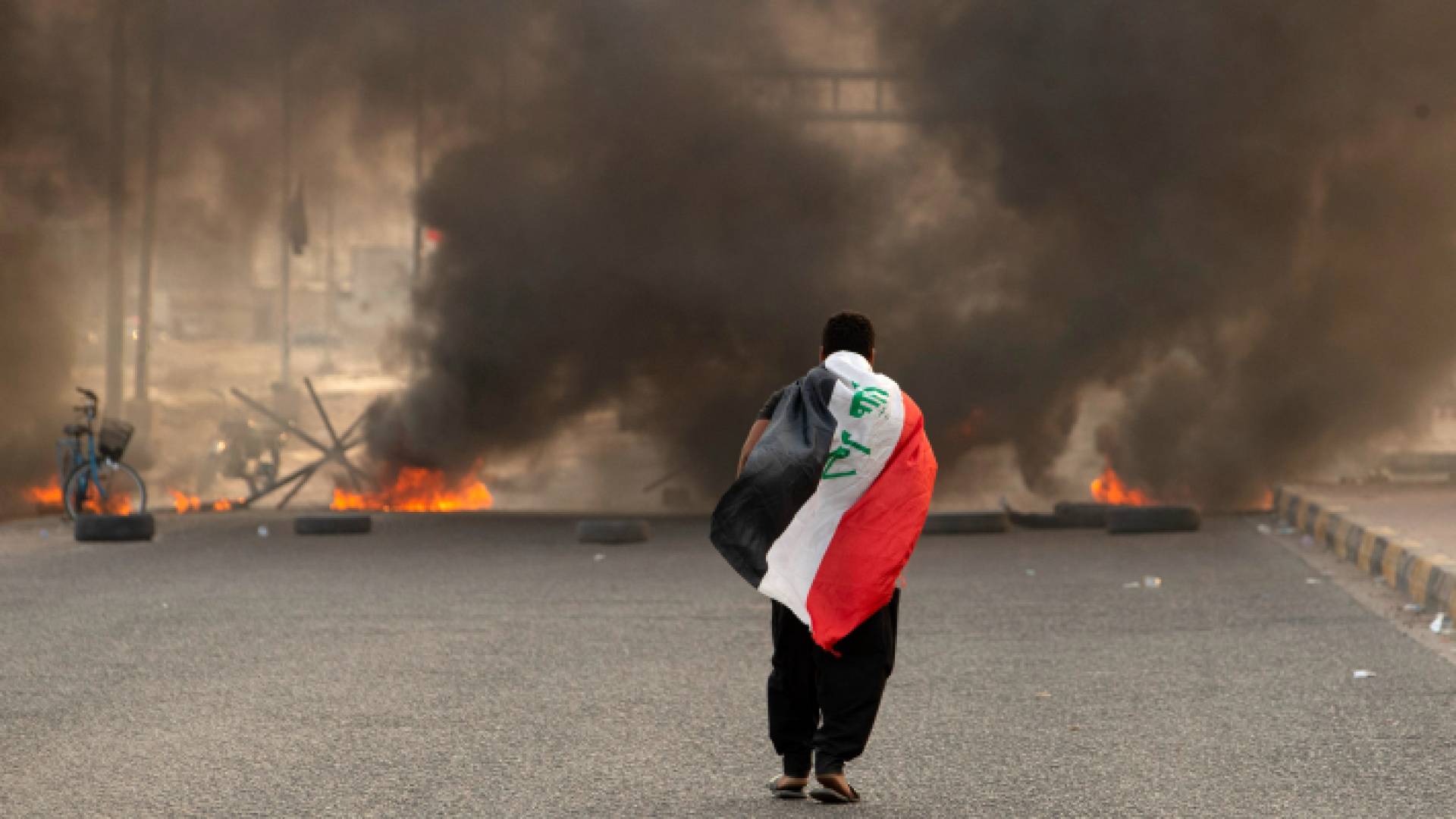 شخص يحمل العلم العراقي أثناء الاضطرابات التي شهدتها البلاد
