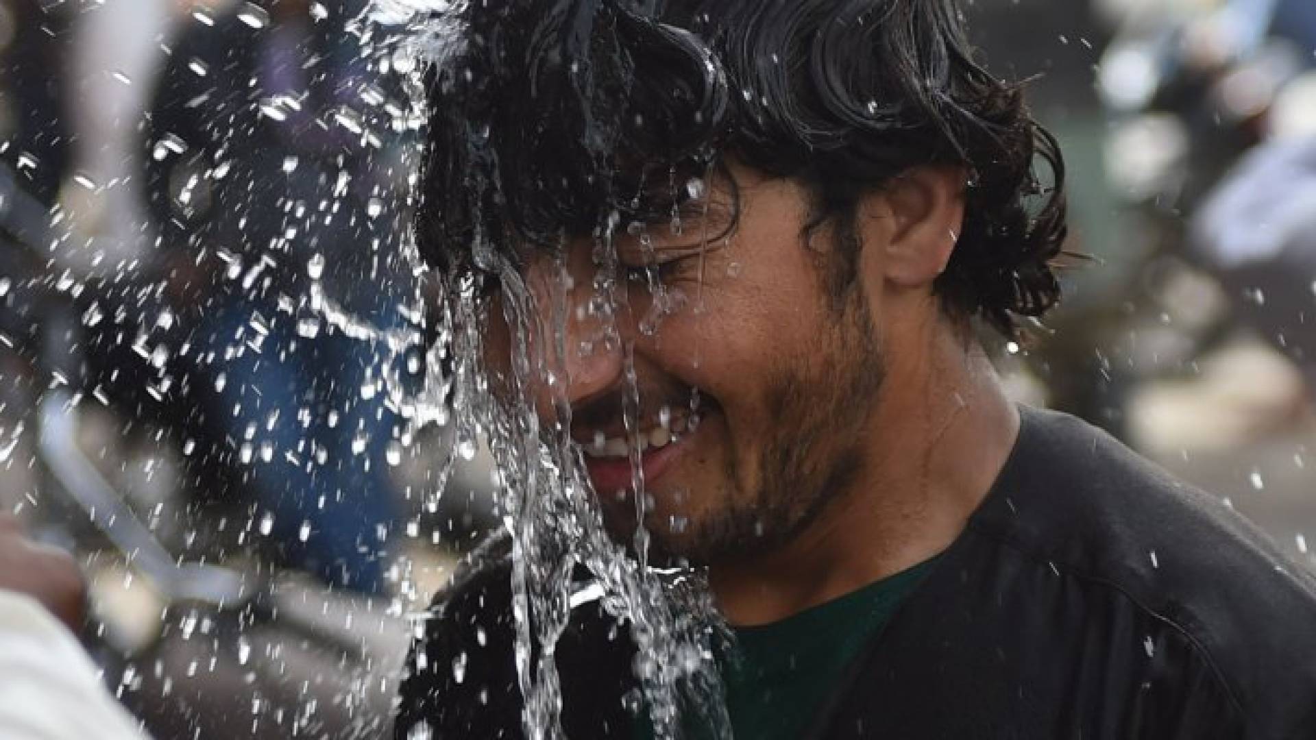 مواطن يسكب الماء على رأسه نتيجة ارتفاع درجات الحرارة