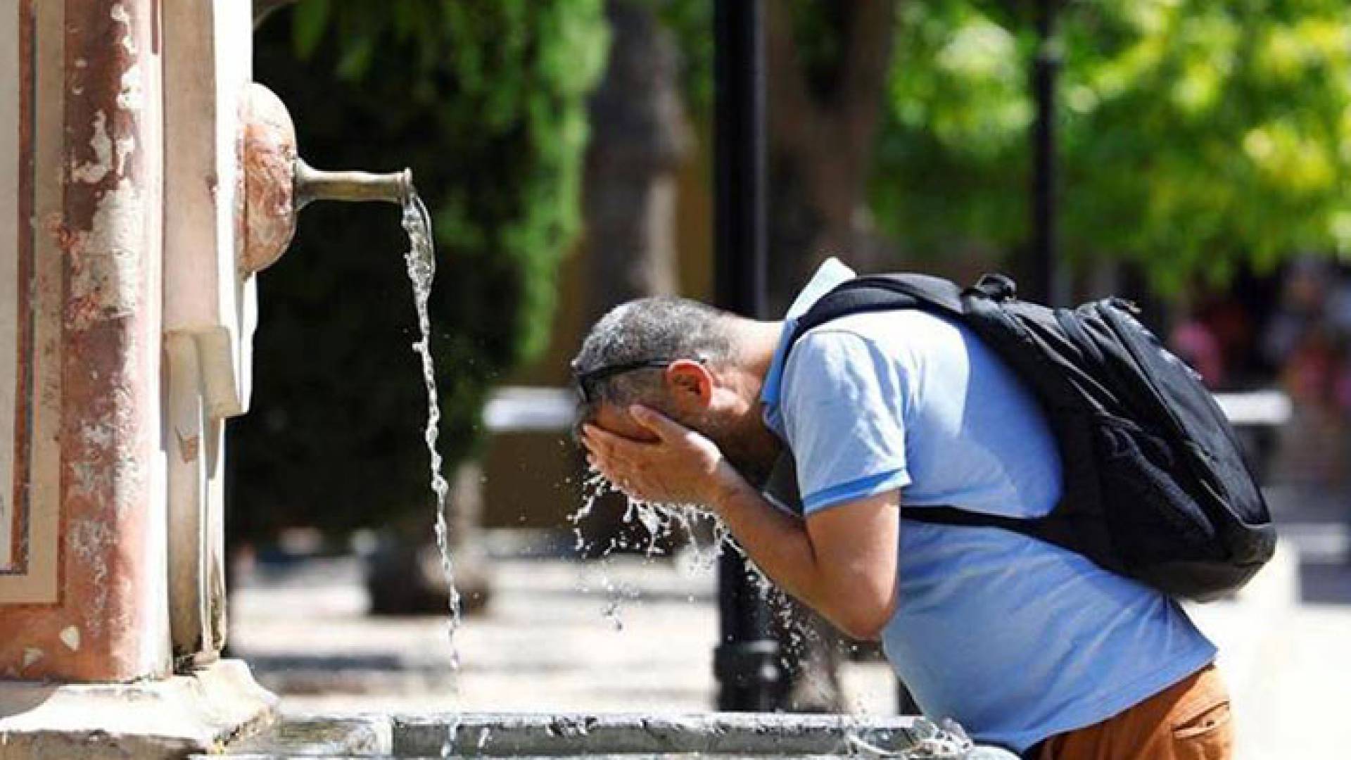 رجل يسكب الماء على وجهه من شدة حرارة الطقس