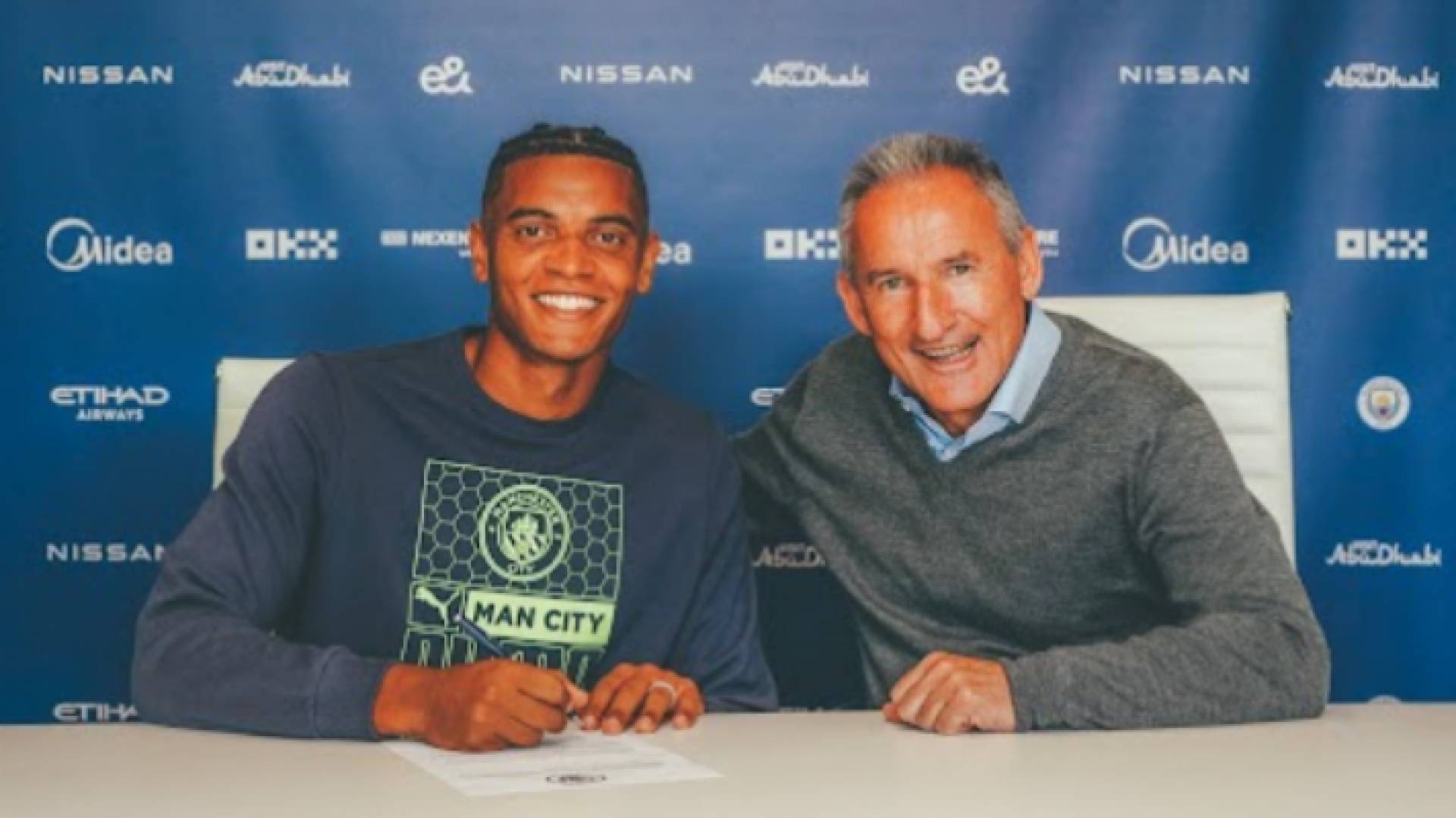 المدافع الدولي السويسري مانويل أكانجي (يسار) في أثناء توقيعه على عقد انتقاله إلى مانشستر سيتي