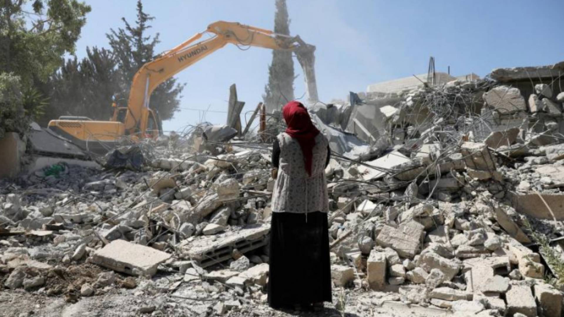 سيدة فلسطينية واقفة على أنقاض منزلها