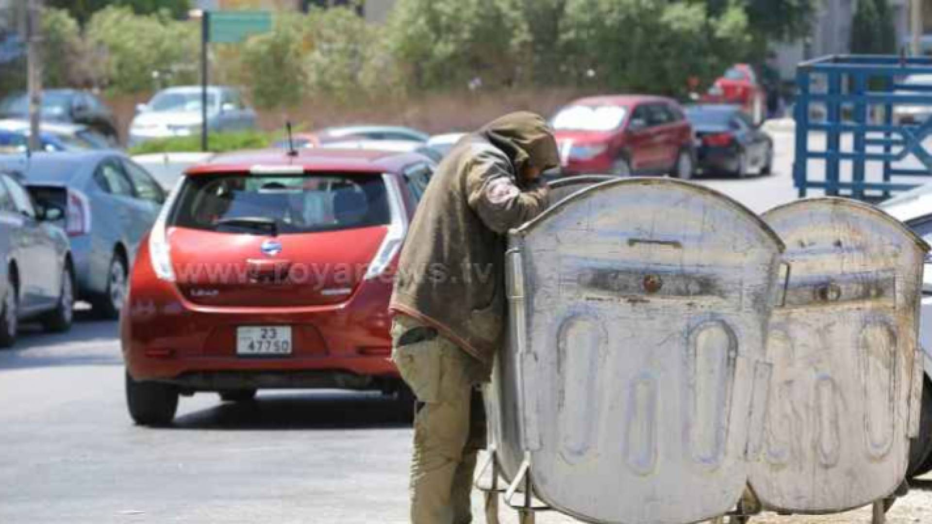 شخص يلتقط النفايات من إحدى الحاويات