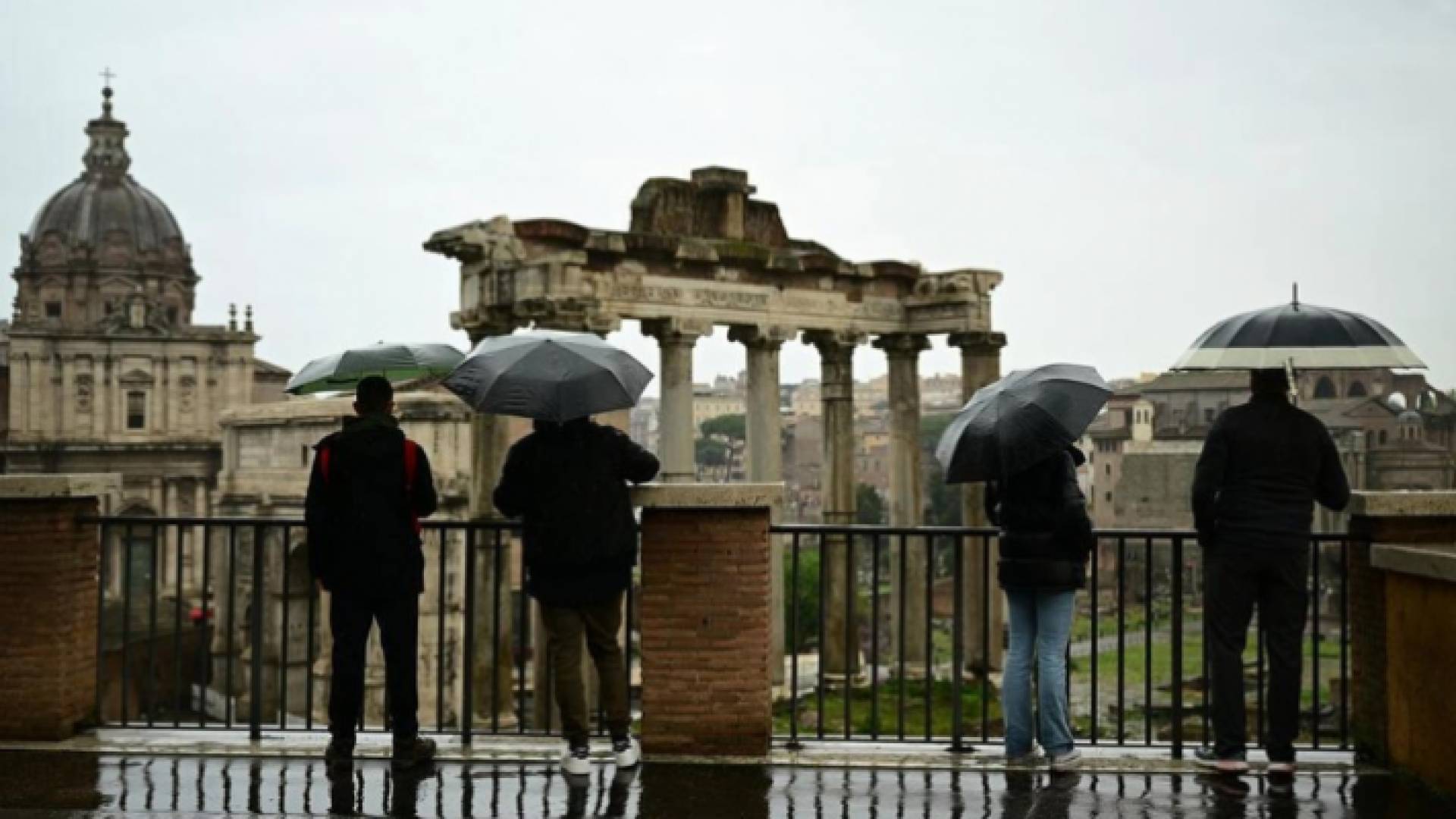صورة أرشيفية لسياح يحملون مظلات تحت المطر أمام المنتدى الروماني في روما