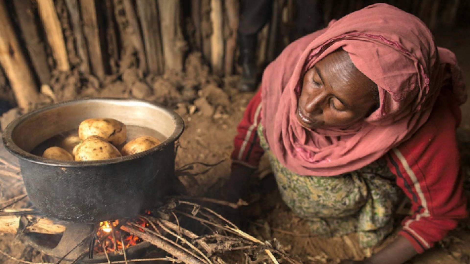 مرأة تحاول صنع الطعام وسط الفقر الشديد