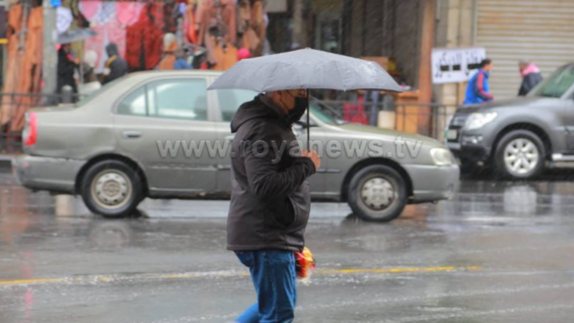 شخص يحمل مظلة تحت المطر في وسط البلد بالعاصمة عمان