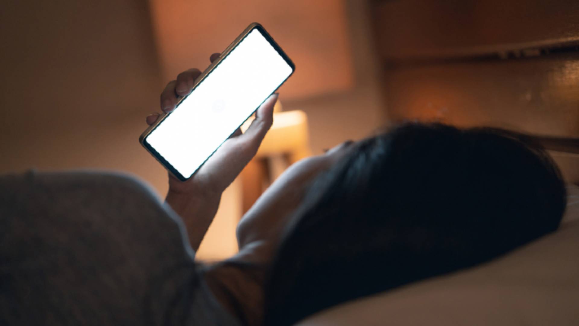 صورة تعبيرية لفتاة تمسك بهاتفها