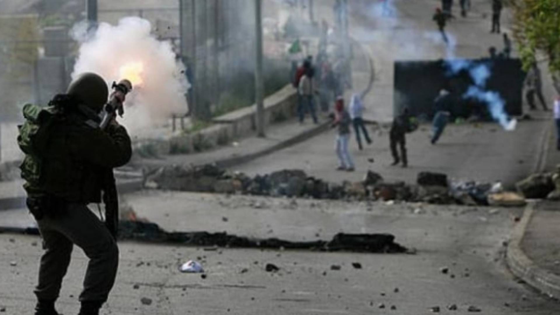 جندي من قوات الاحتلال يصوب بندقيته نحو فلسطينيين